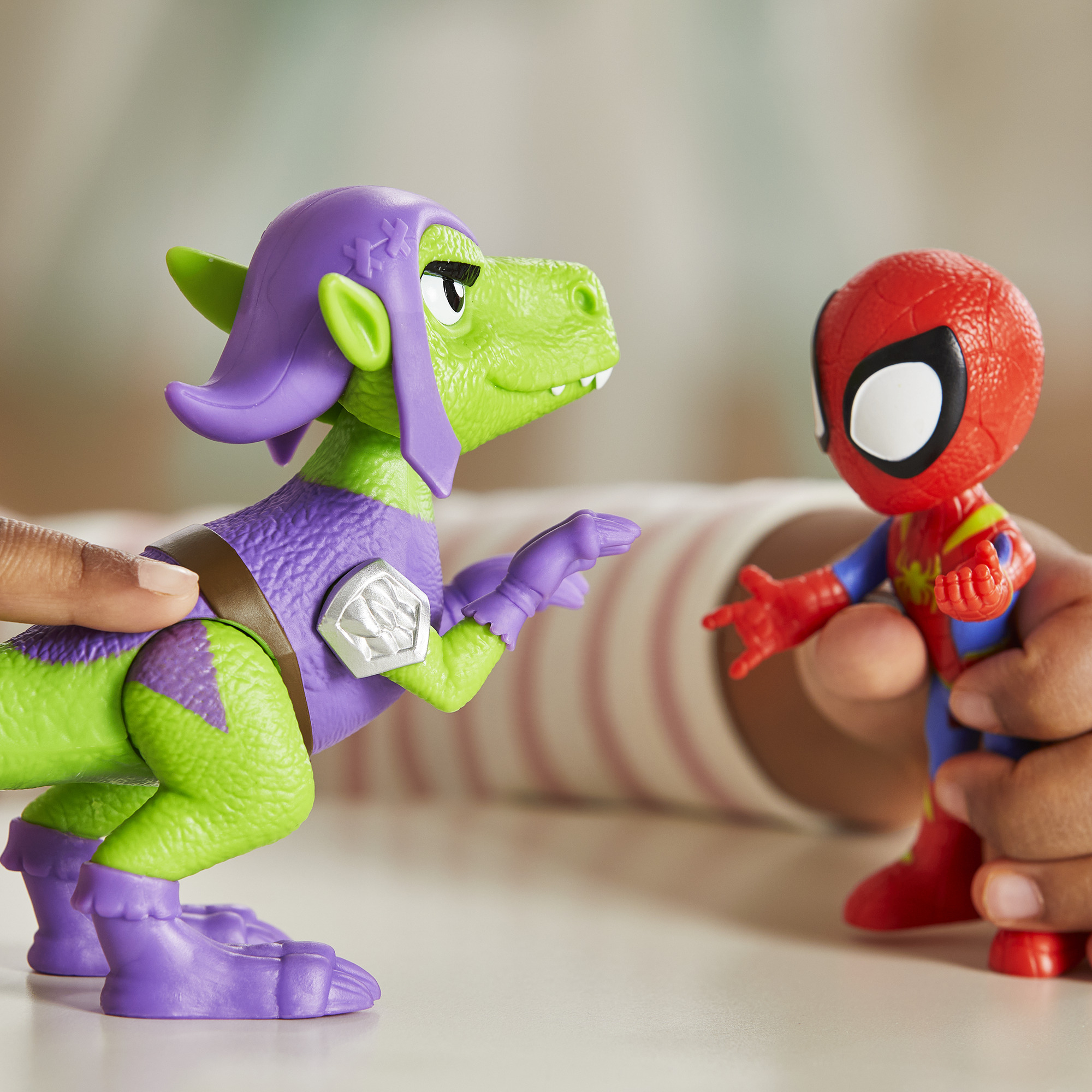 Juguete de dinosaurio Duende Verde frente a juguete Spider-Man con brazos extendidos. Ambas manos.