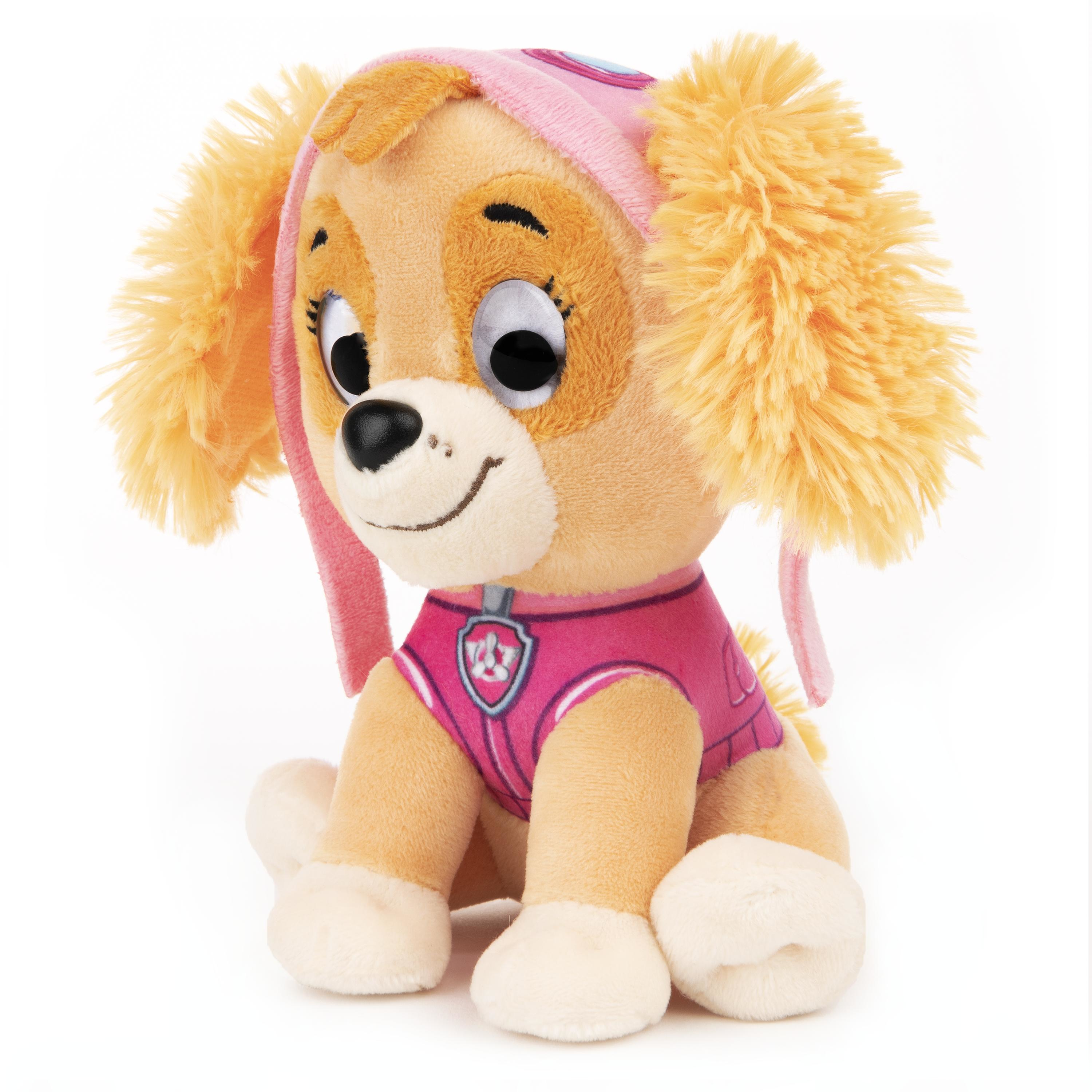 Ein Plüschtier Skye von Paw Patrol sitzt auf einer weißen Oberfläche. Sie trägt Rosa, hat große Augen und lächelt.