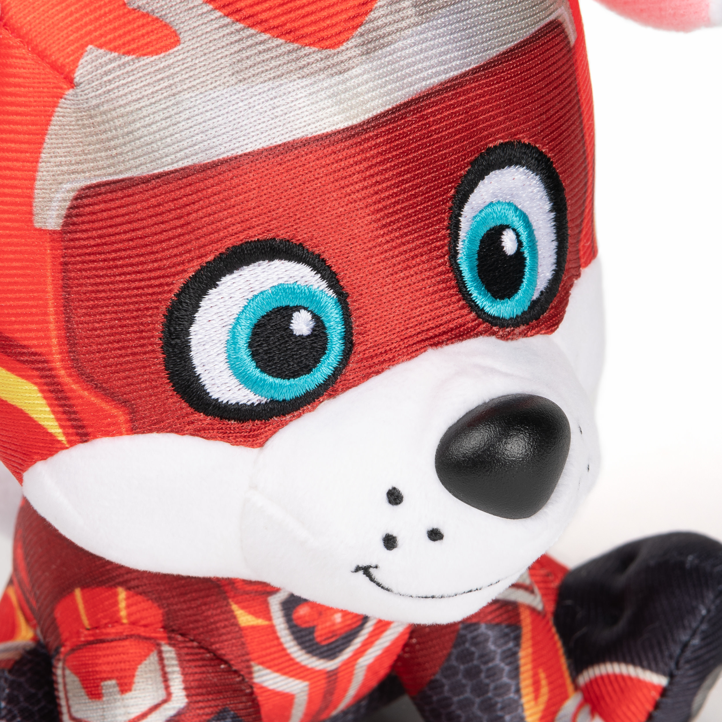 Primer plano de la cara de un perro de peluche. El perro tiene un disfraz de superhéroe rojo y azul. Nariz blanca.