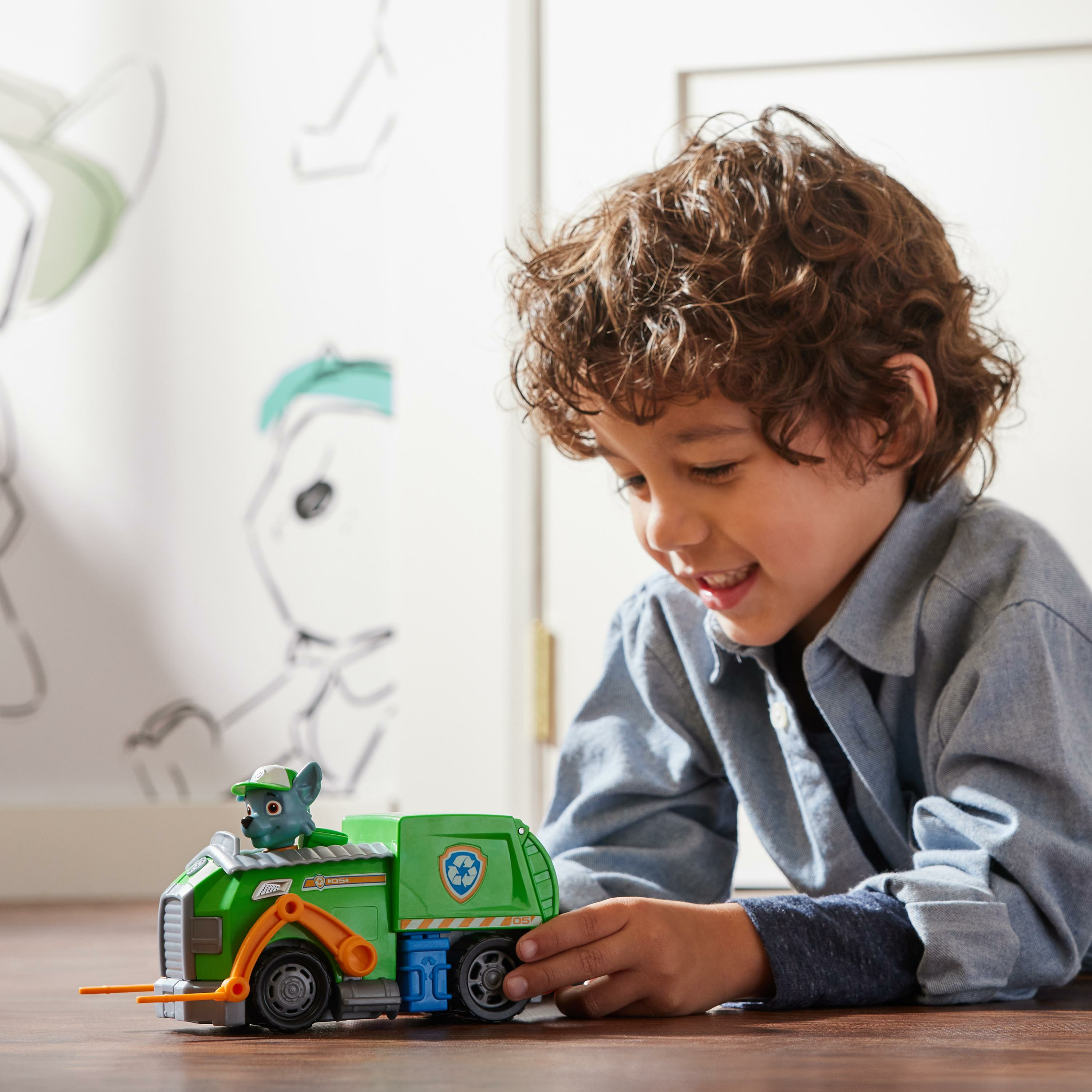 Junge spielt mit einem grünen Paw Patrol Spielzeug-Müllwagen.