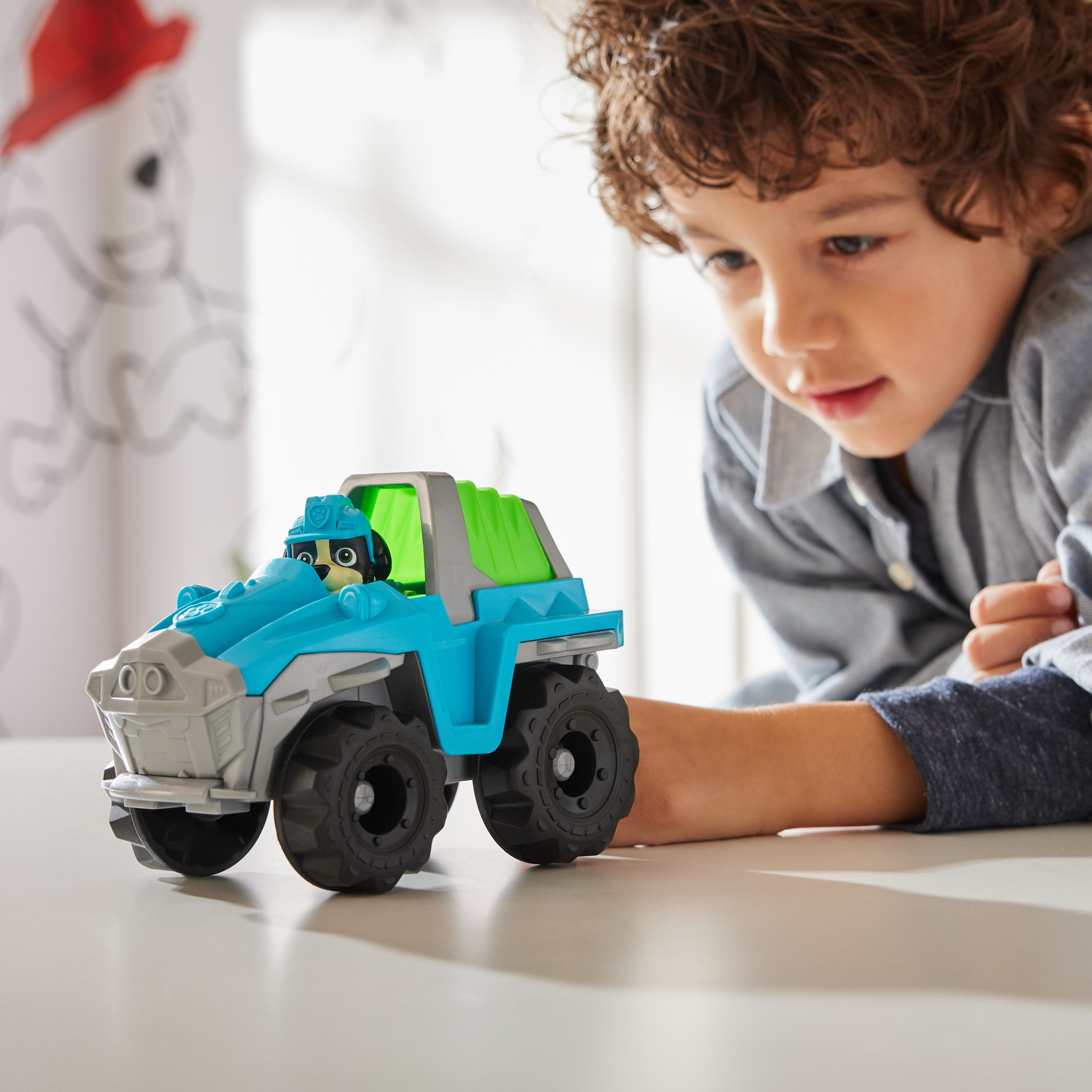 Junge betrachtet Spielzeugauto. Weißer Tisch, weißer Hintergrund.