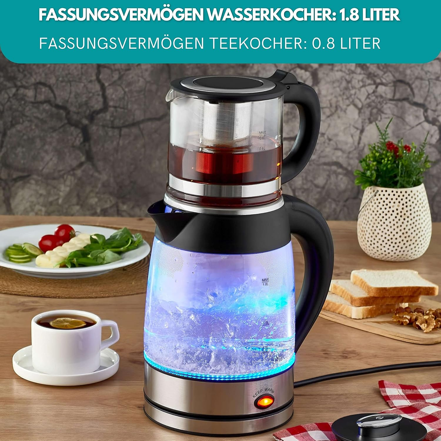 Elektrischer Glaskessel mit blauem Licht. Teekanne oben, Tasse Tee, Toast und eine kleine Pflanze in der Nähe.