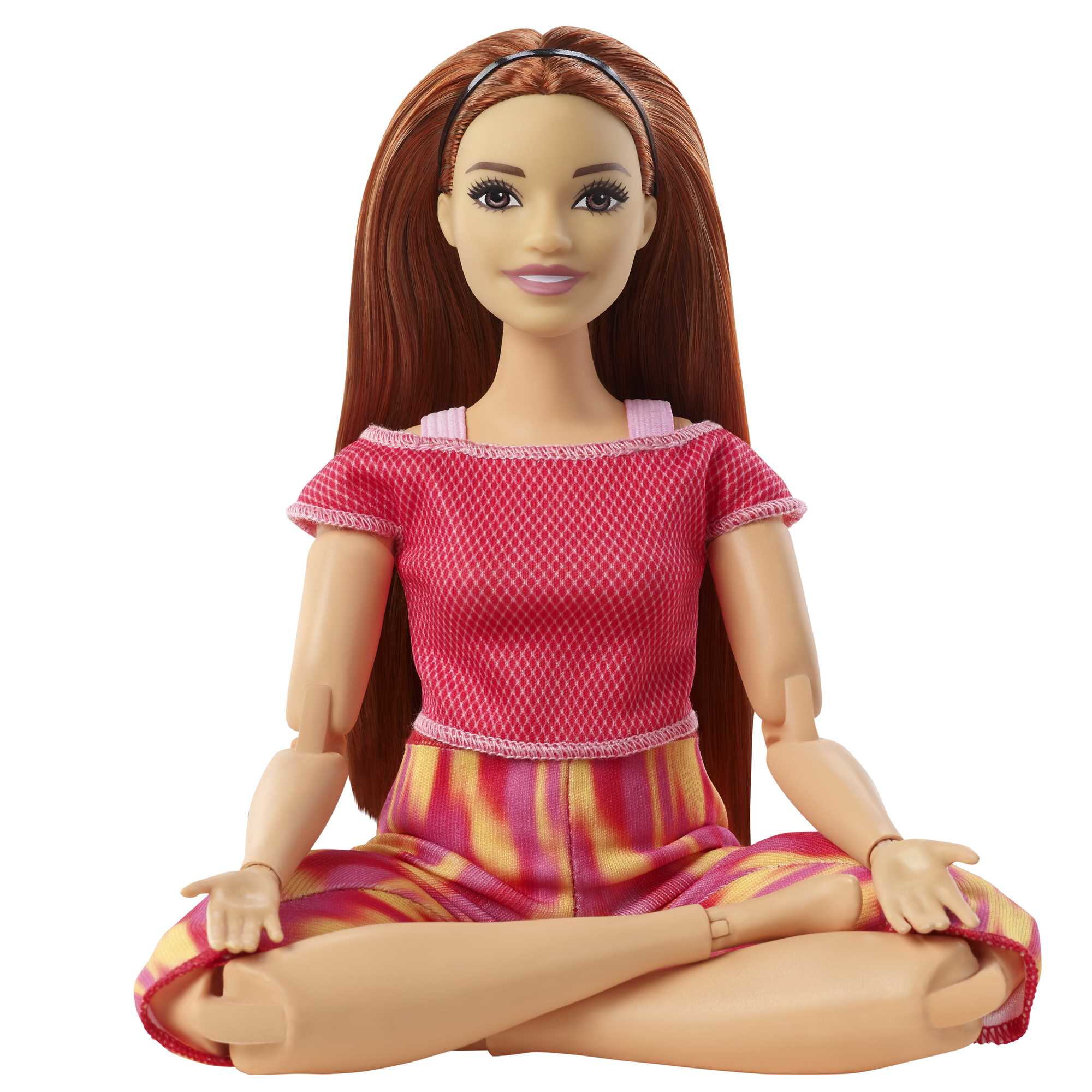 Eine Puppe einer Frau in Yoga-Pose, die ein rosa Oberteil und bunte Hosen trägt.