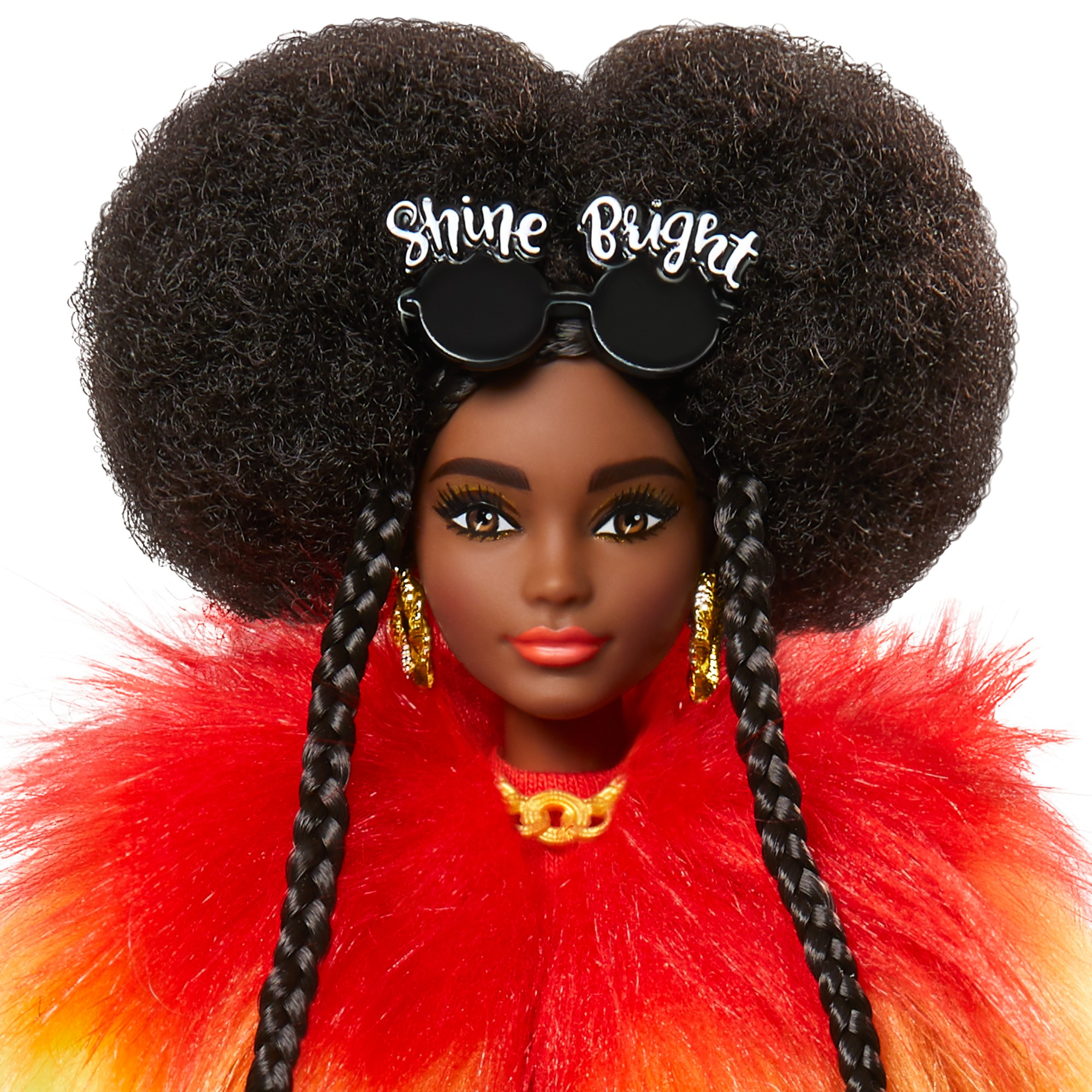 Nahaufnahme des Gesichts einer Barbie-Puppe. Sie hat dunkle Haut, einen großen Afro mit Sonnenbrille und rot-orangefarbenes Fell.