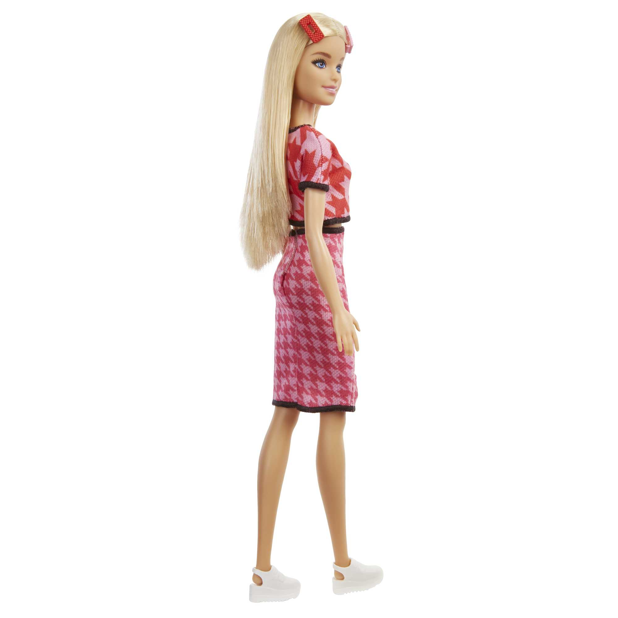 Vista lateral de una muñeca Barbie con un vestido estampado rojo y rosa y zapatos blancos, con una diadema roja.