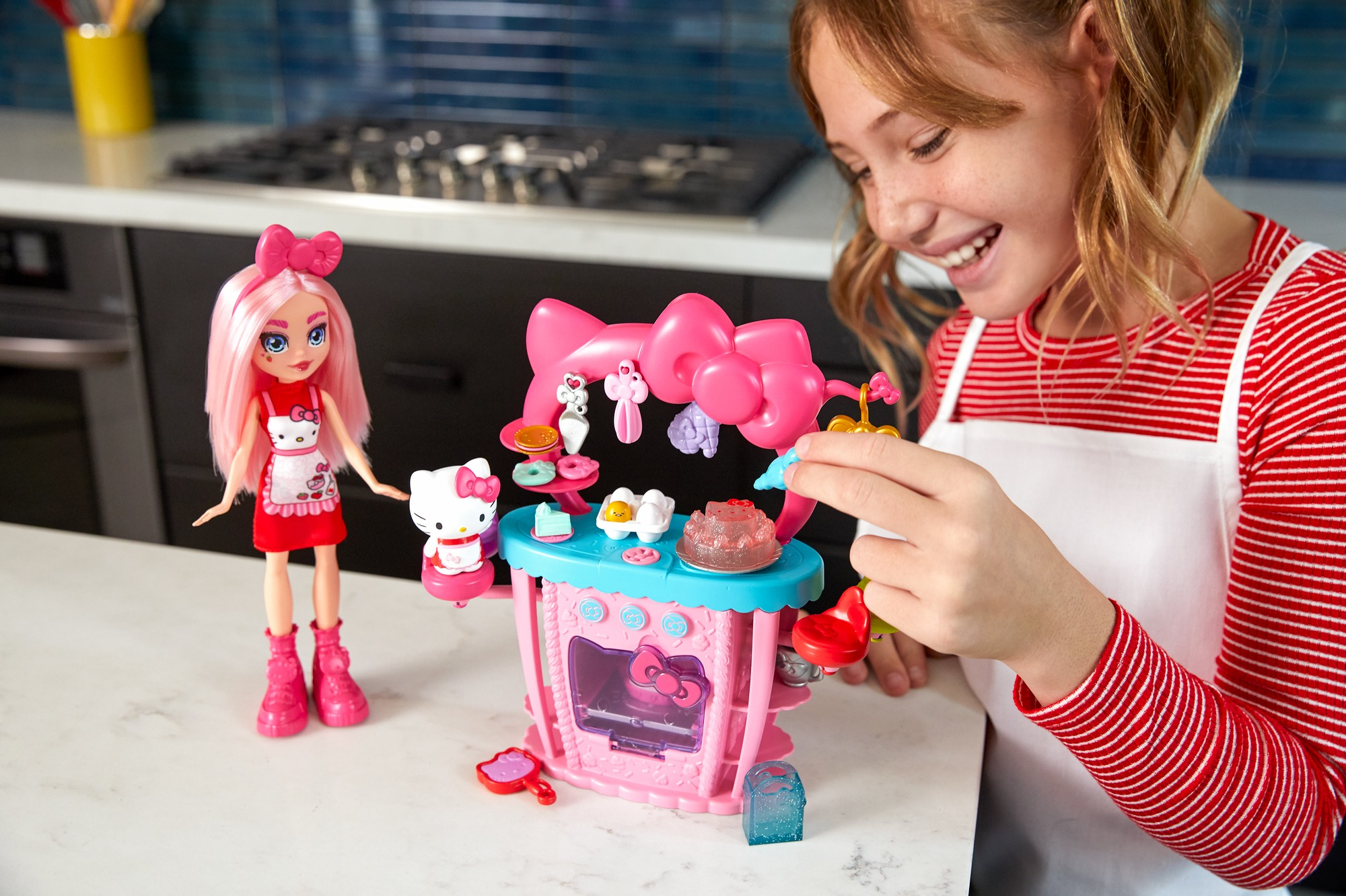 Una ragazza che gioca con un set da cucina giocattolo di Hello Kitty, con una bambola accanto alla cucina.