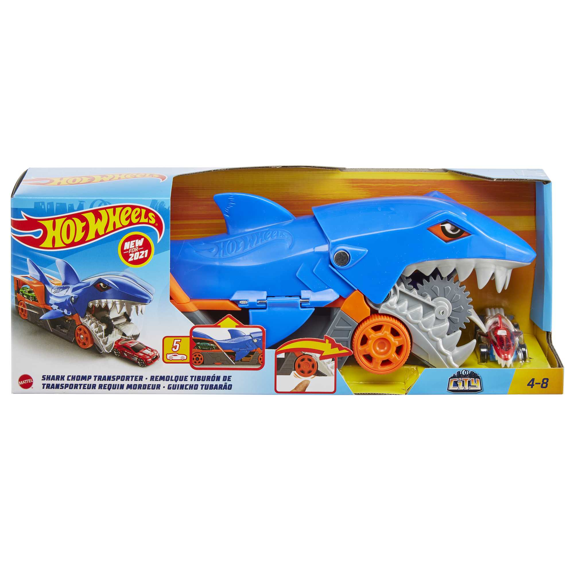 Camión de juguete Hot Wheels en embalaje. Camión azul con forma de tiburón, ruedas naranjas y un coche rojo pequeño.