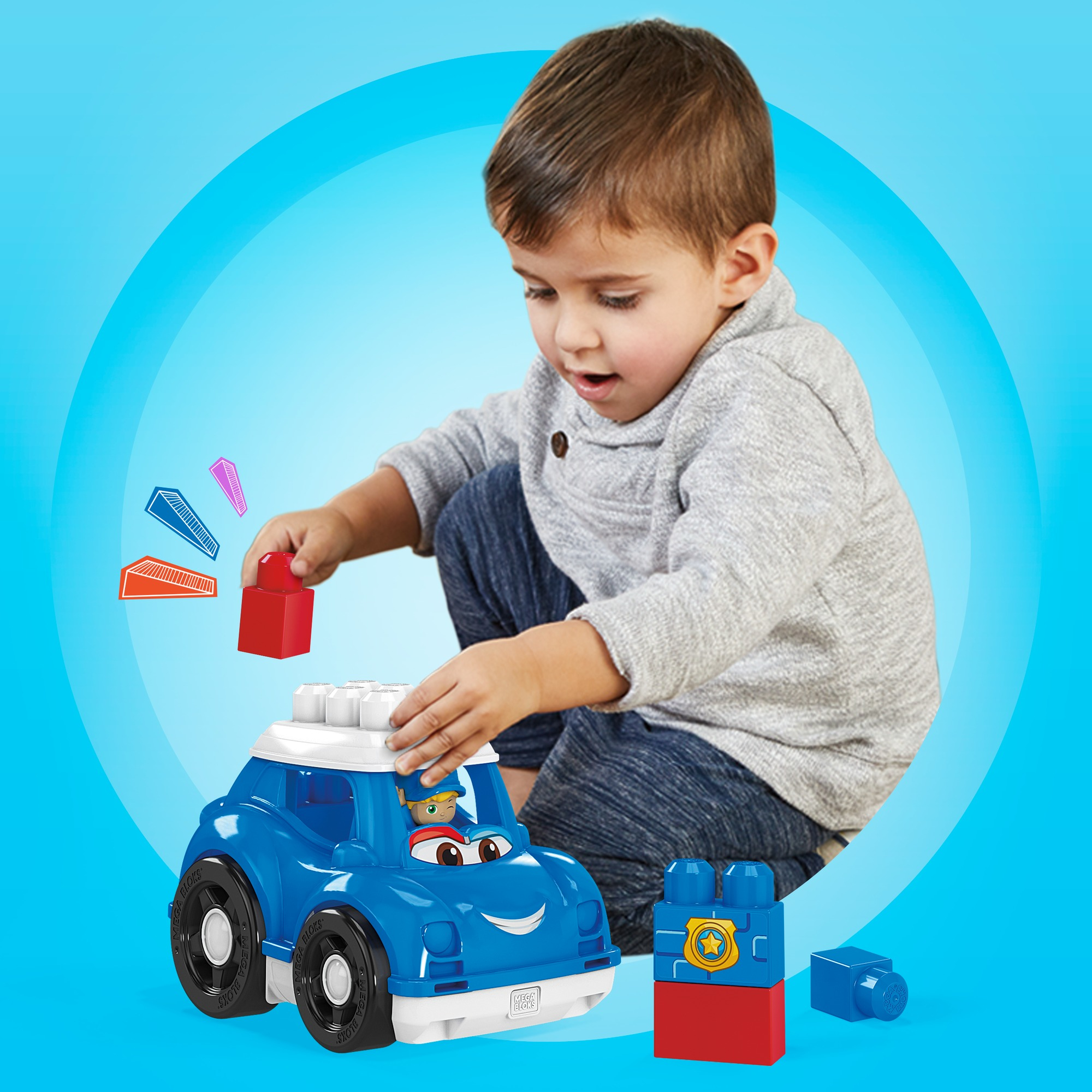 Ein Kind spielt mit Spielzeugblöcken und einem blauen Polizeiauto. Blauer Hintergrund.