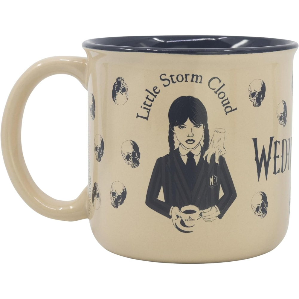 Taza beige con Wednesday Addams y calaveras. Texto: Little Storm Cloud, Wednesday. Borde interior oscuro.