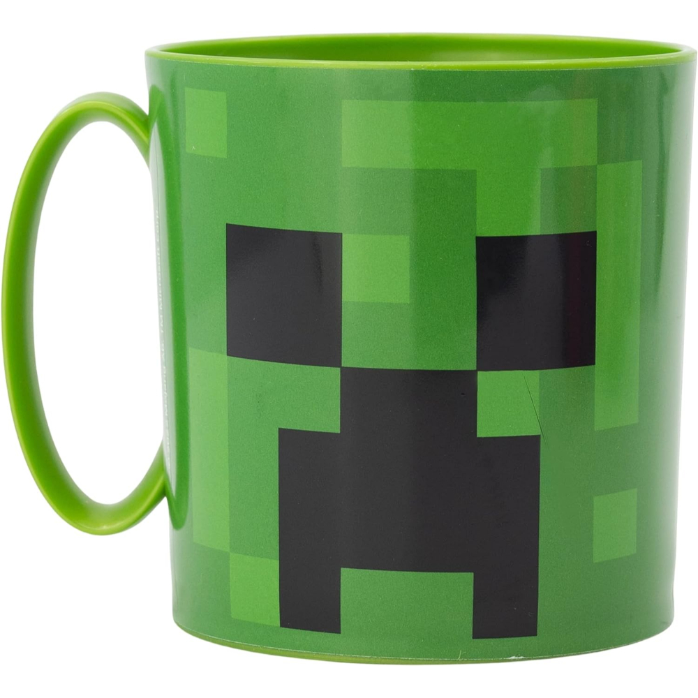 Una taza Creeper de Minecraft verde, con diseño de cara cuadrada y asa verde, sobre una superficie blanca.