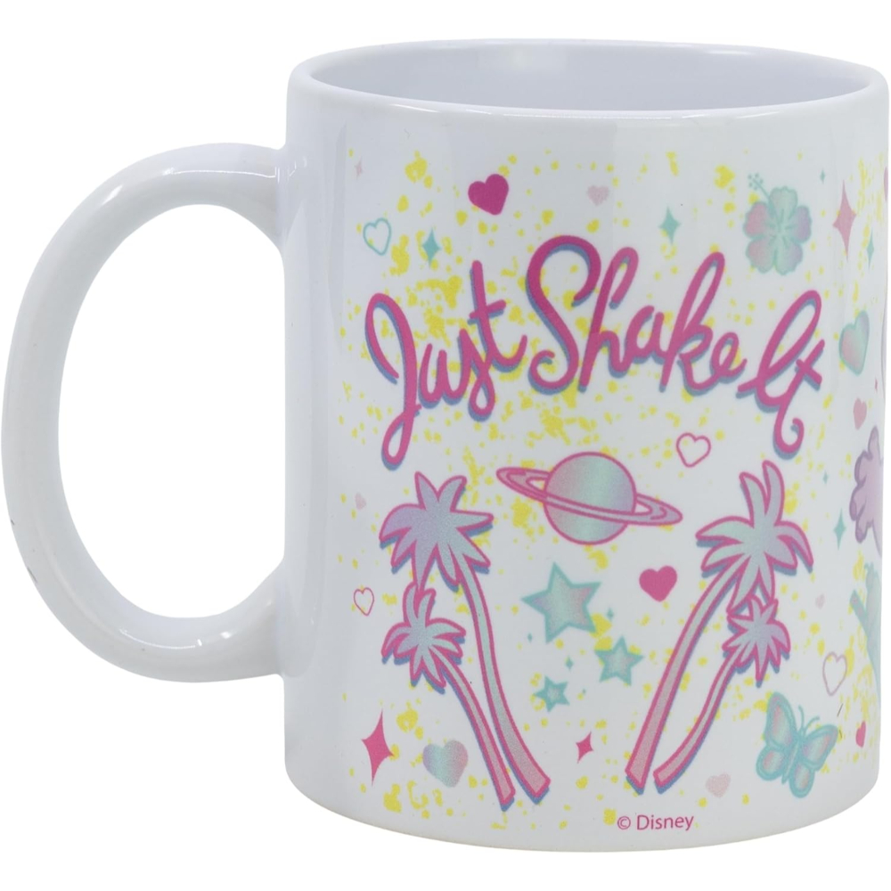 Taza blanca con diseño colorido. 'Just shake it' está escrito en rosa. También se muestran palmeras, corazones y estrellas.