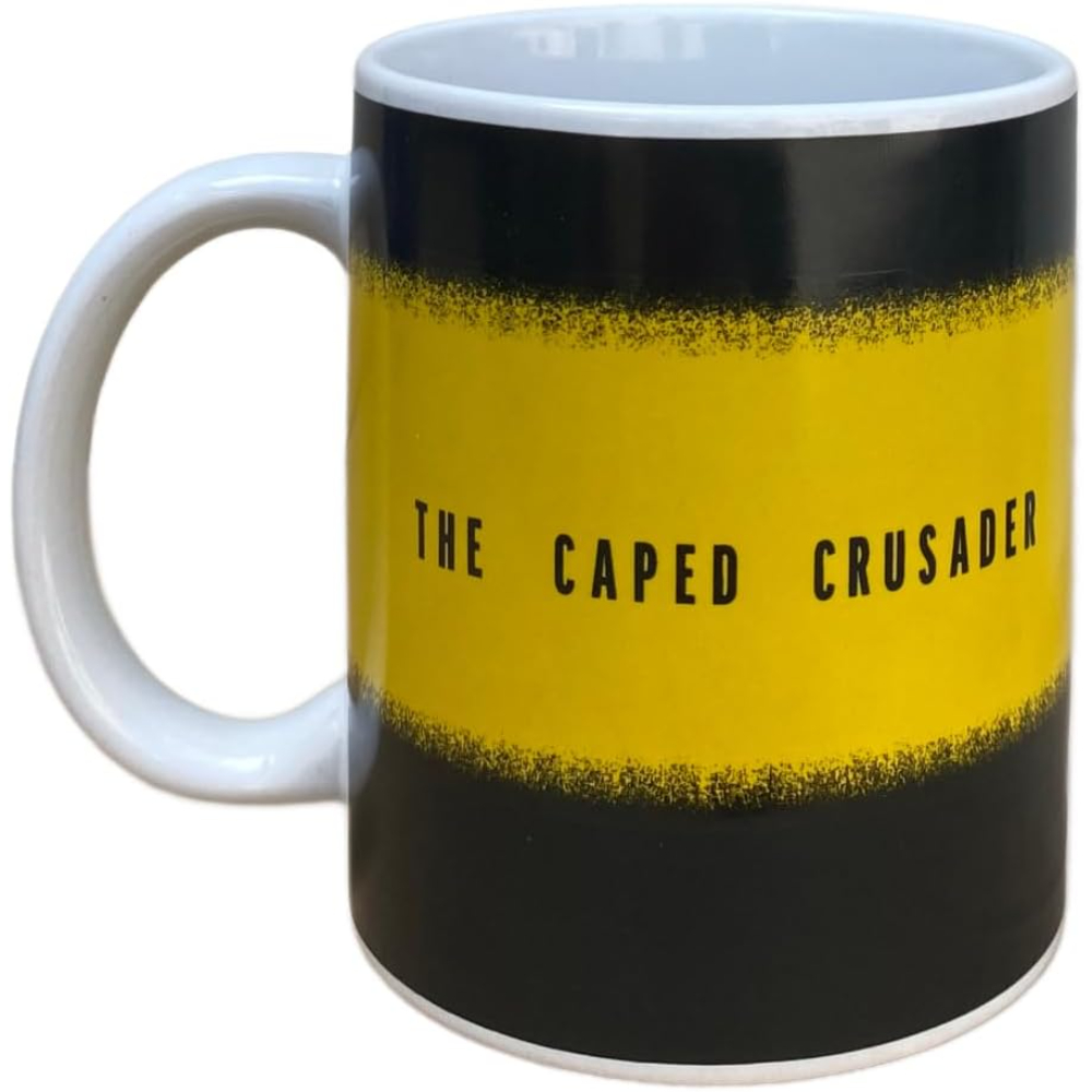 Taza con rayas negras y amarillas. Texto: THE CAPED CRUSADER. Asa blanca.