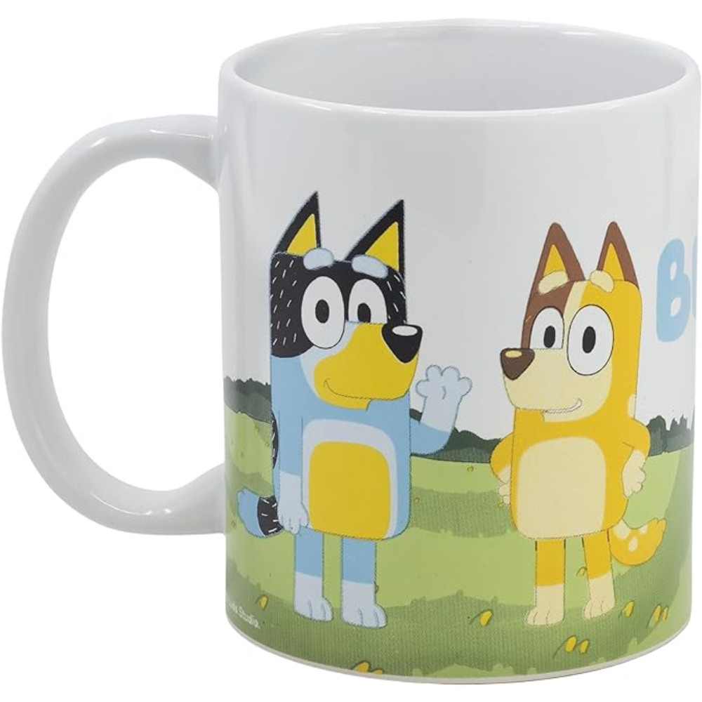 Taza blanca con Bluey y Bingo de la caricatura Bluey. Bluey es azul, Bingo es naranja. Fondo verde.