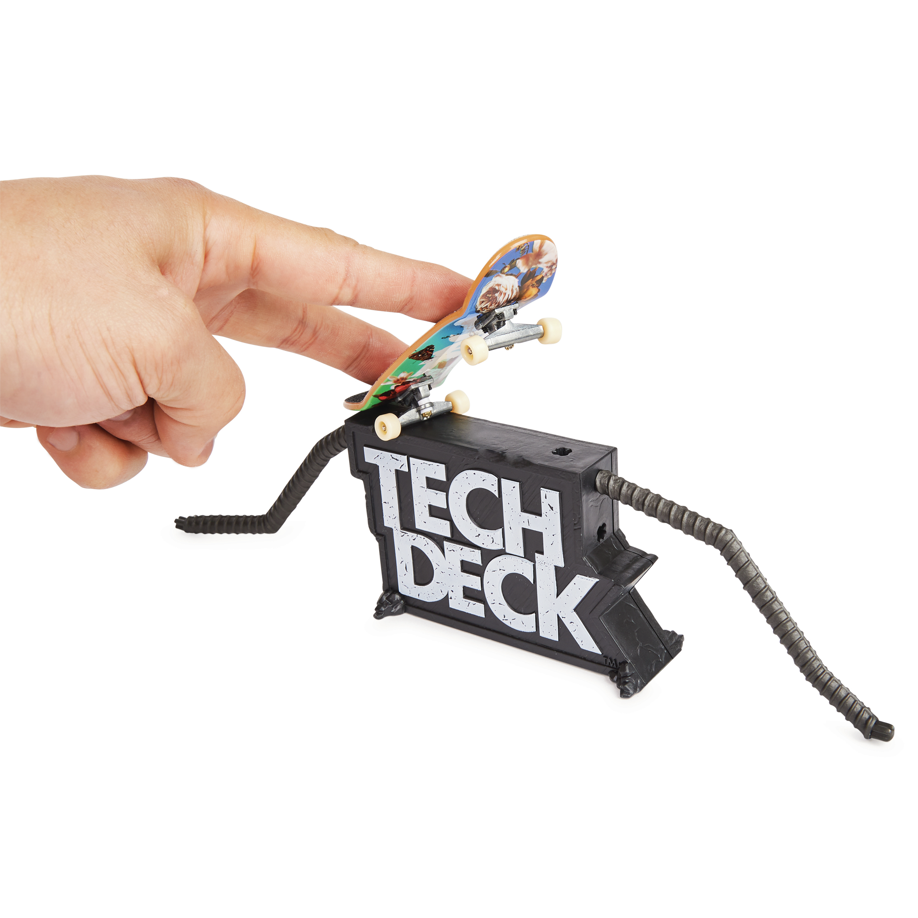 Eine Hand balanciert ein kleines Skateboard auf einer schwarzen Rampe mit dem Schriftzug 'TECH DECK'.