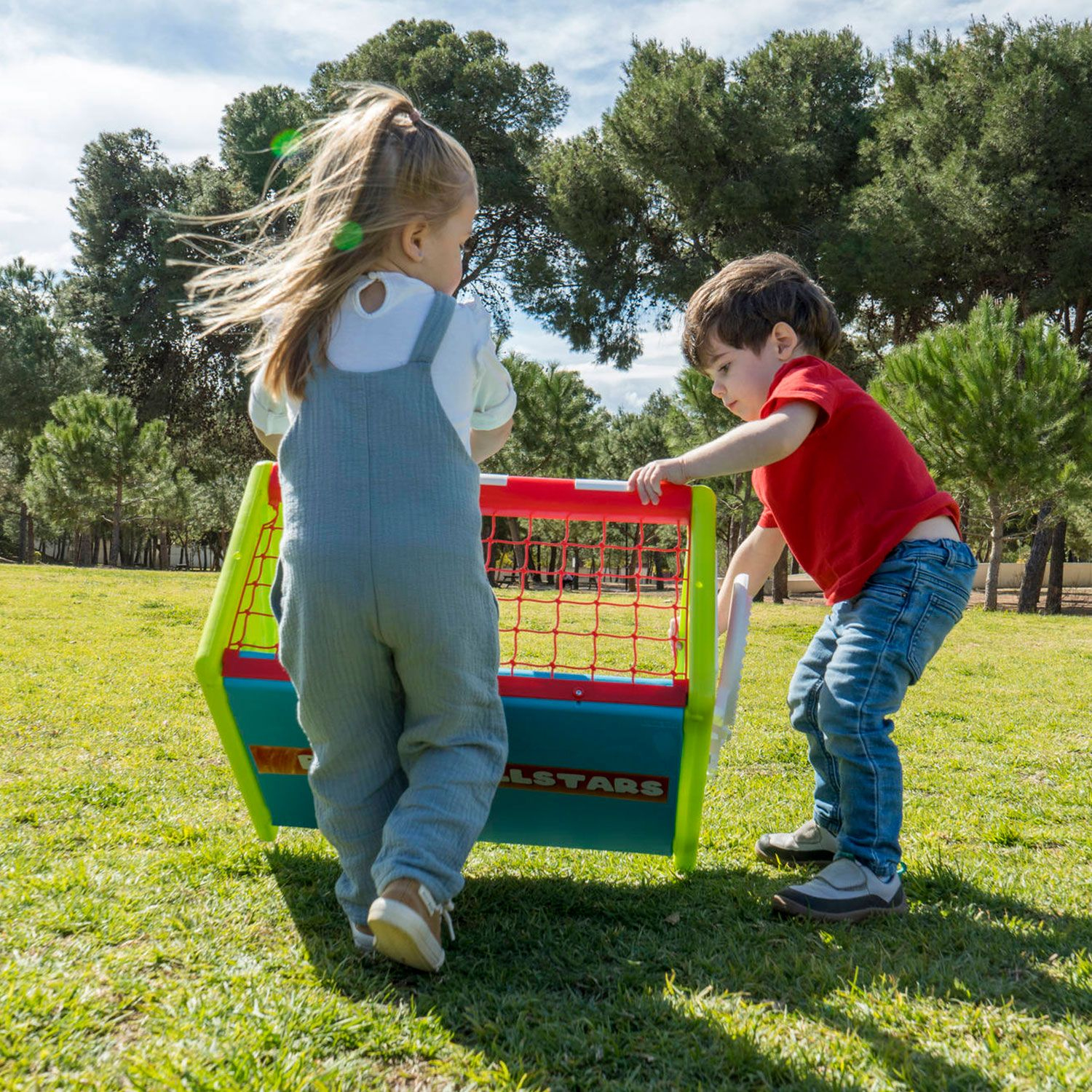 Due bambini che giocano con una porta da calcio su un campo erboso sotto un cielo soleggiato.