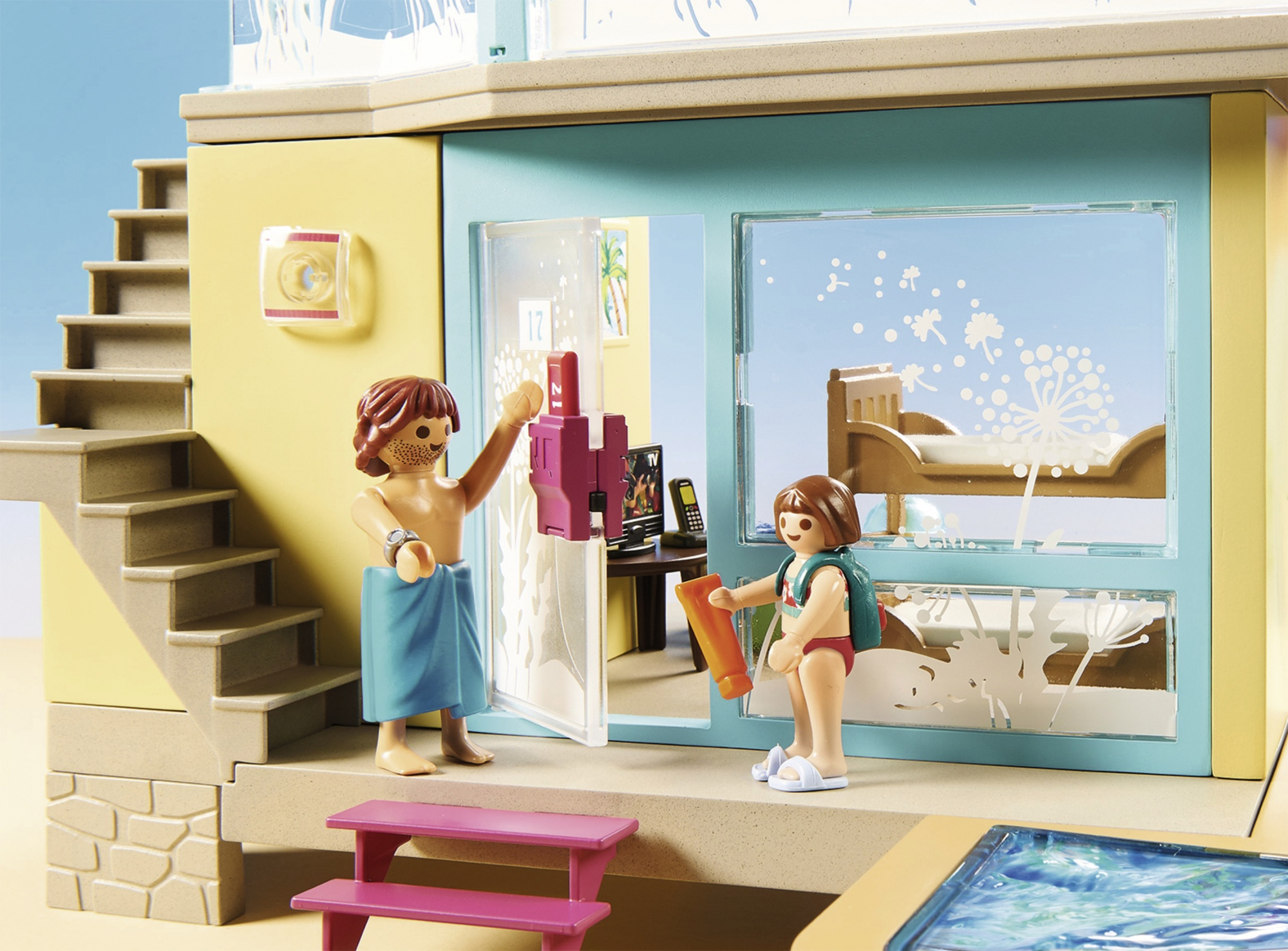 Juego de Playmobil con dos figuras. Un hombre en toalla y una mujer con mochila en un edificio.