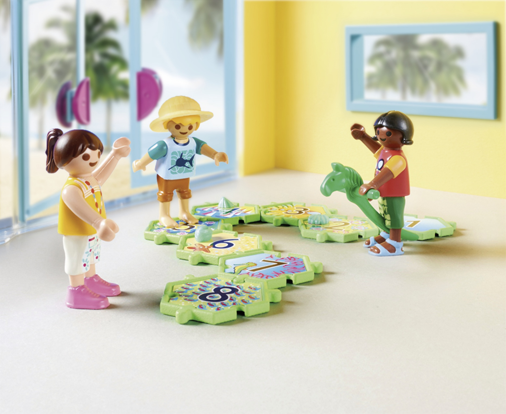 Trzy figurki Playmobil bawią się puzzlami w zestawie o tematyce plażowej.