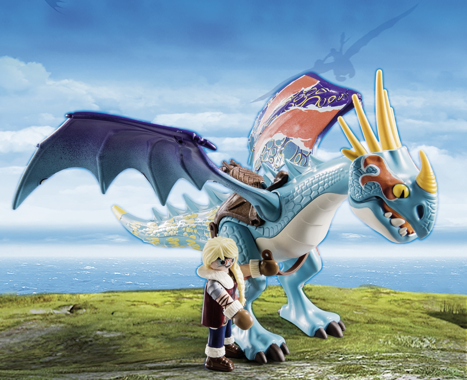 Ein Spielzeugdrache mit einer Person. Der Drache ist blau und weiß, und die Person ist blond.