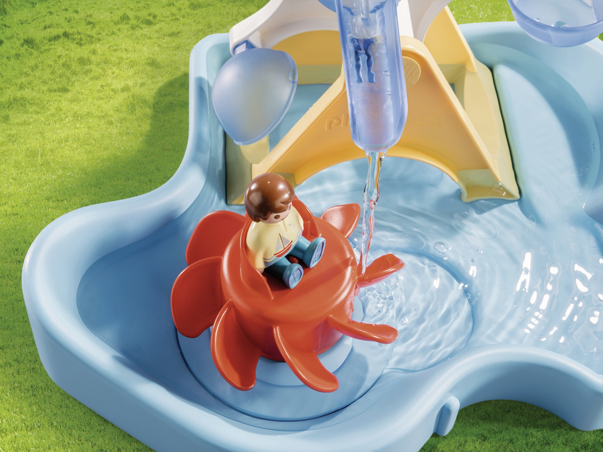 Figurka dziecka siedzi na czerwonym kole wodnym w niebieskim zestawie do zabawy wodą z płynącą wodą.