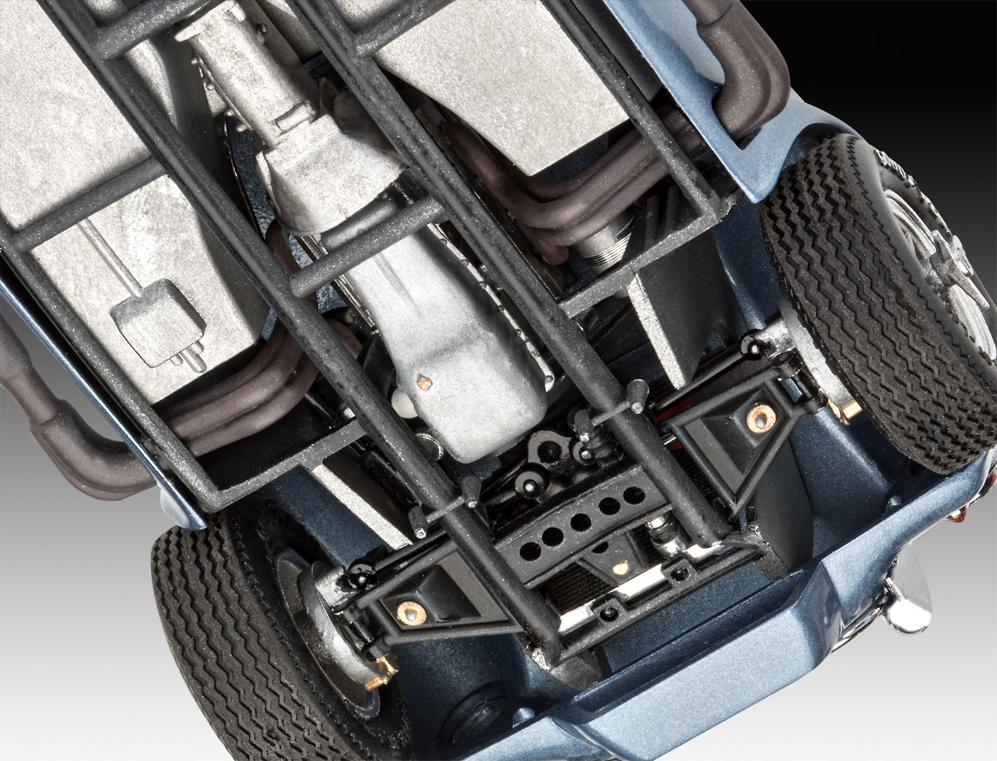 Unterseite eines blauen Modellautos. Fahrgestell, Motor, Auspuffrohre und Räder sind sichtbar.