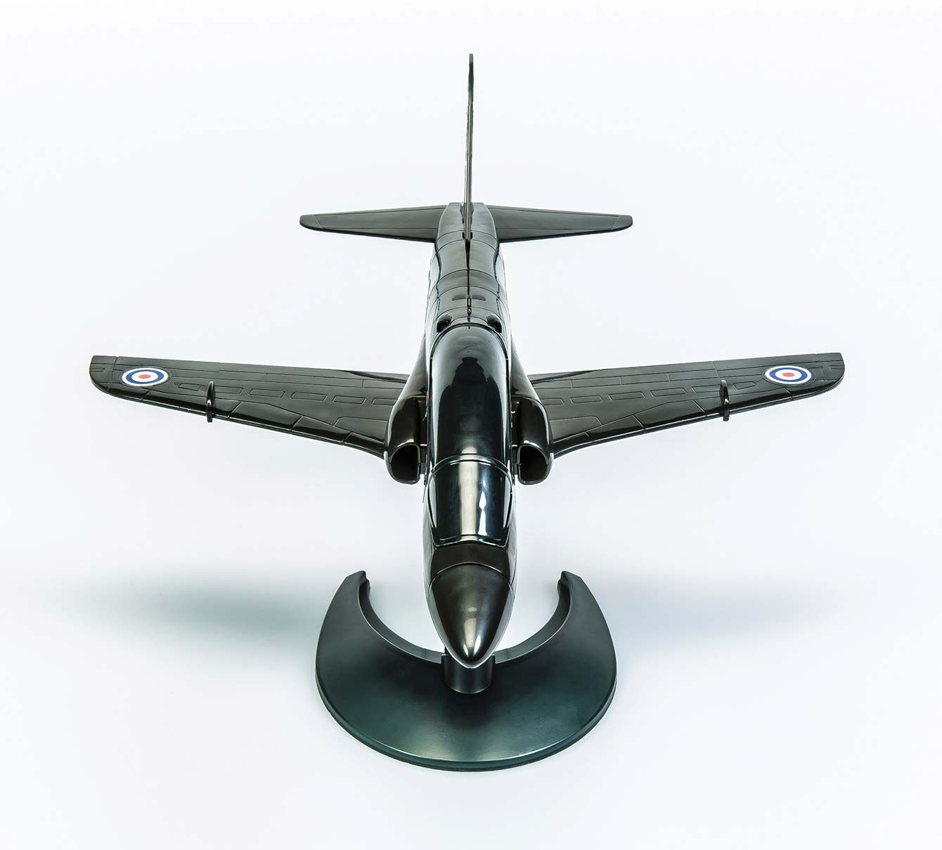 Dunkelgraues Modellflugzeug auf weißem Hintergrund. Draufsicht. Flügel und Schwanz sichtbar.