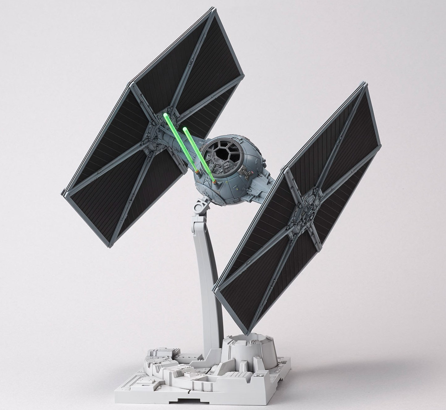 Un modello di caccia TIE di Star Wars con ali aperte, esposto su un supporto con una spada laser.