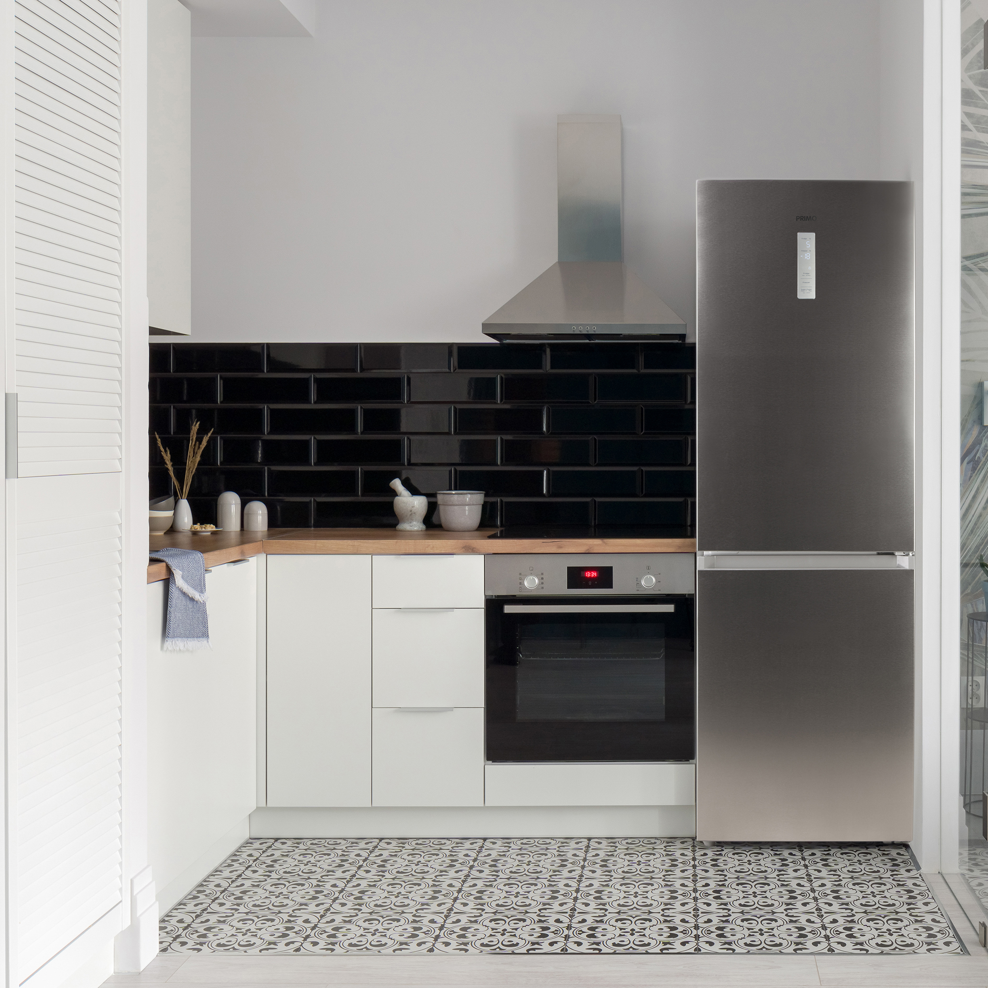 Kitchen with black tile backsplash, white cabinets, and a stainless steel fridge.