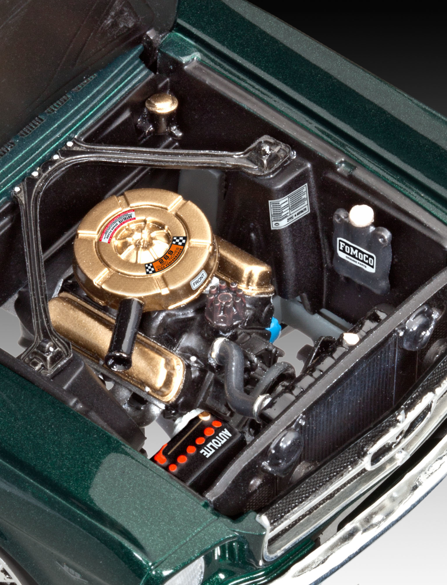 Close-up van een modelauto-motor, met gedetailleerde componenten in een donkere setting.