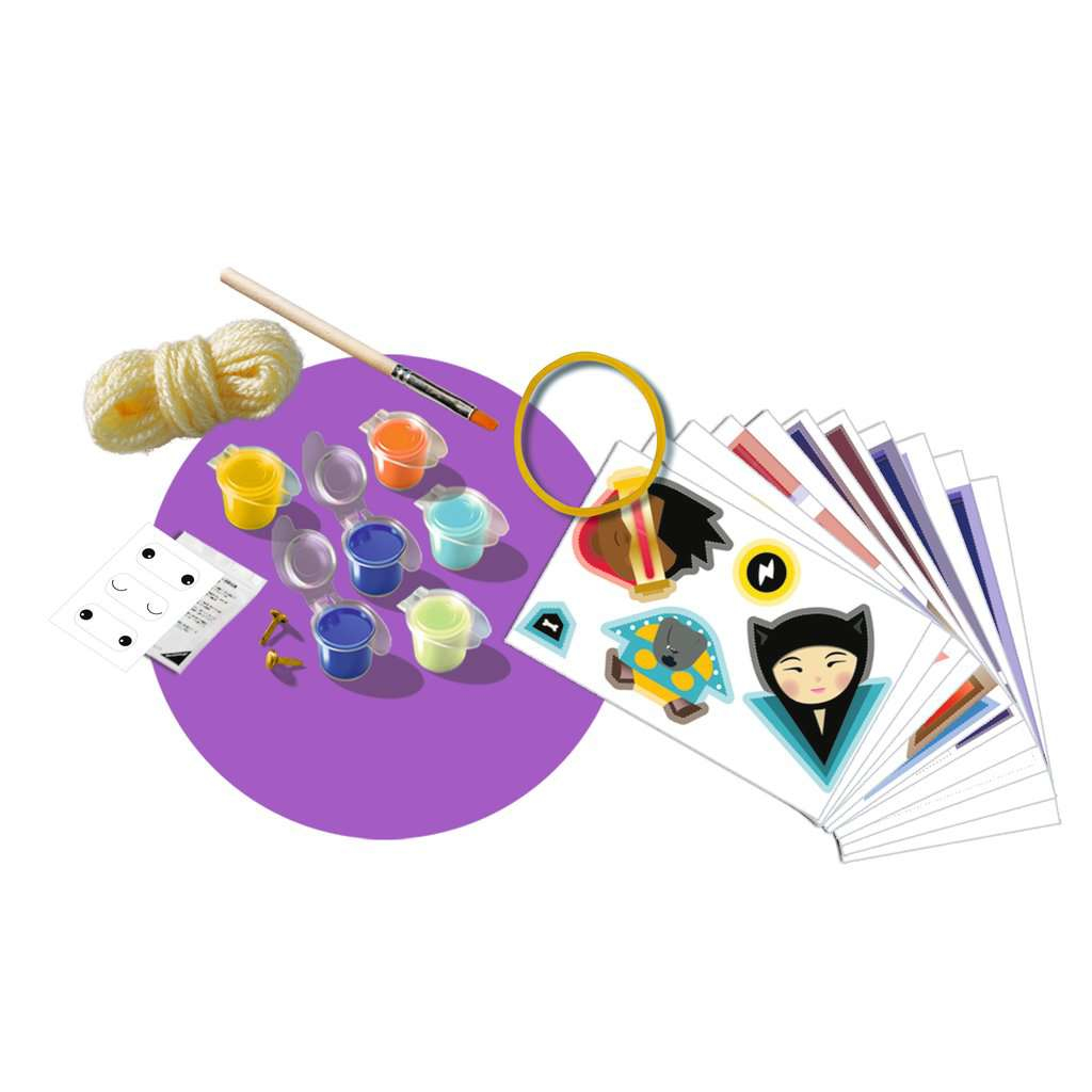 Bastelset mit Farbtöpfen, einem Pinsel, Aufklebern und Bastelmaterialien auf einer Oberfläche angeordnet.