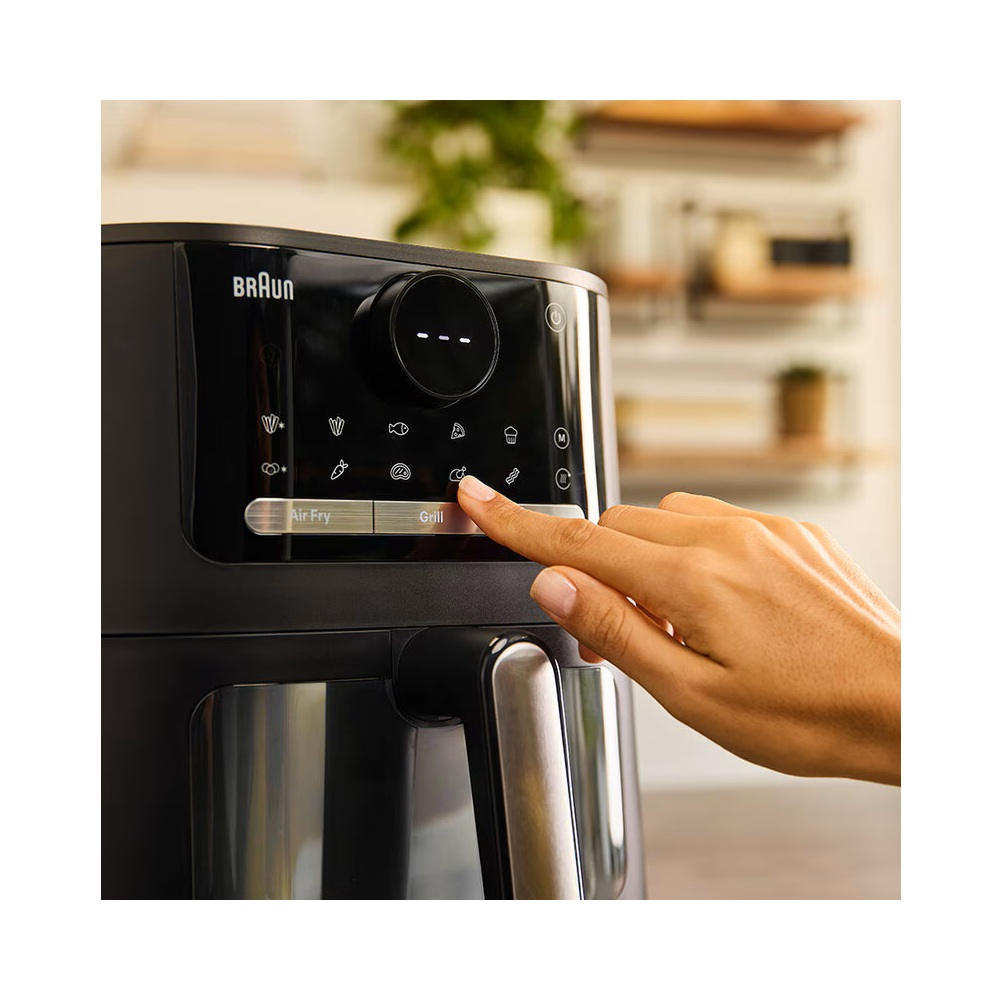 Ręka osoby naciska przycisk grill w czarnej frytkownicy powietrznej.