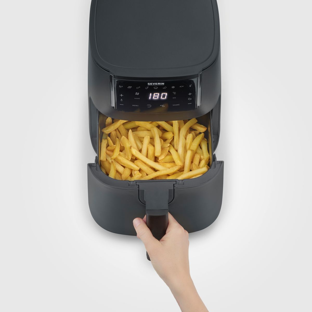 Zwarte airfryer met friet, hand op de handgreep.