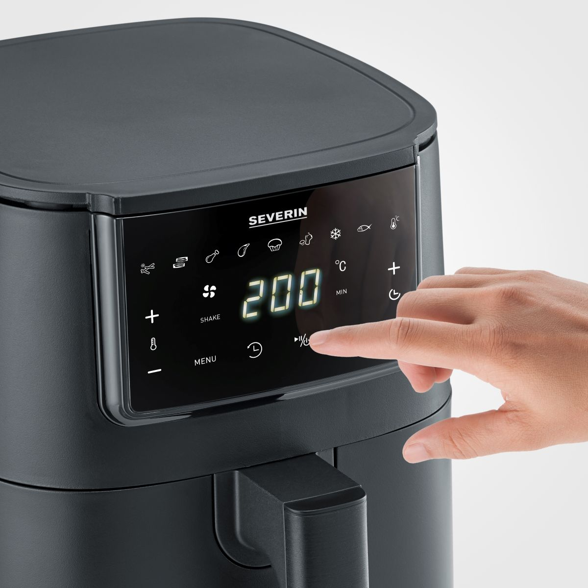 Zwarte airfryer met digitaal display met 200 graden Celsius. Hand raakt scherm aan.