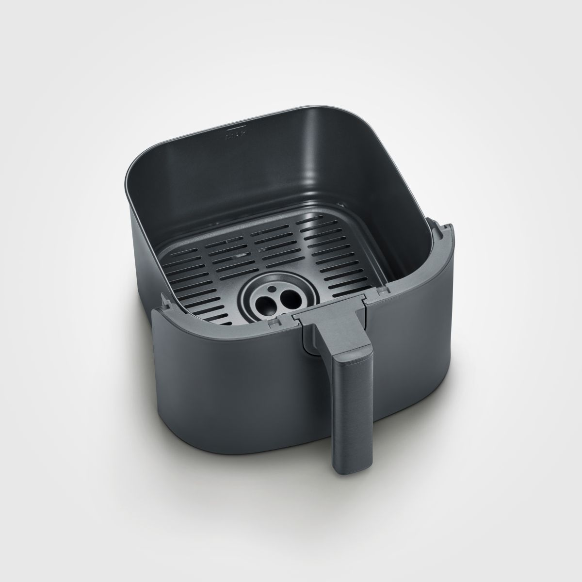 Een lege, donkergrijze airfryer mand staat op een wit oppervlak. Het heeft een handvat en een roosterbodem.