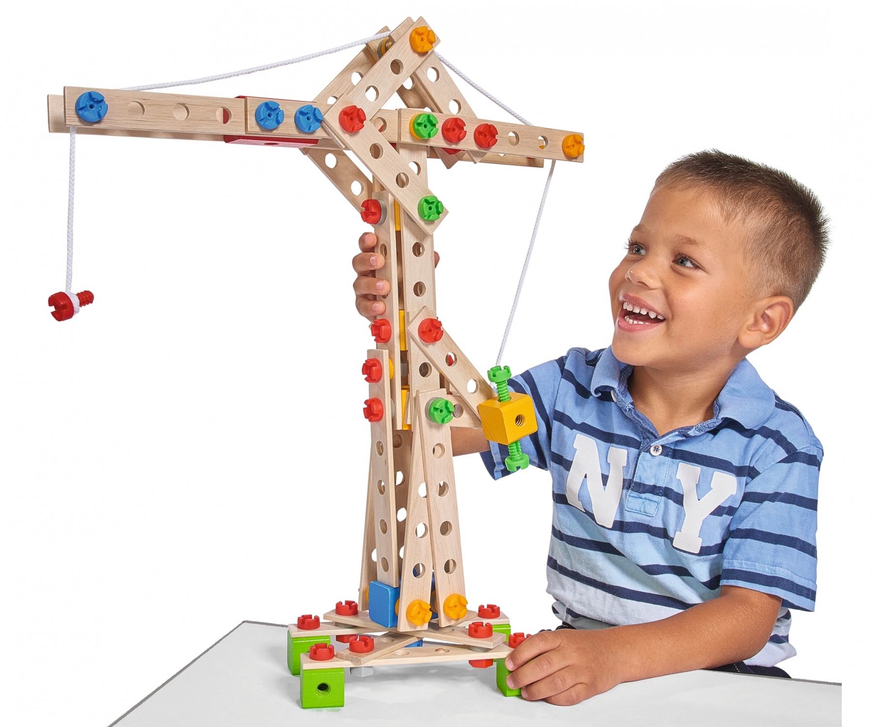 Ein Junge spielt mit einem hölzernen Kranspielzeug, lächelt, weißer Hintergrund.