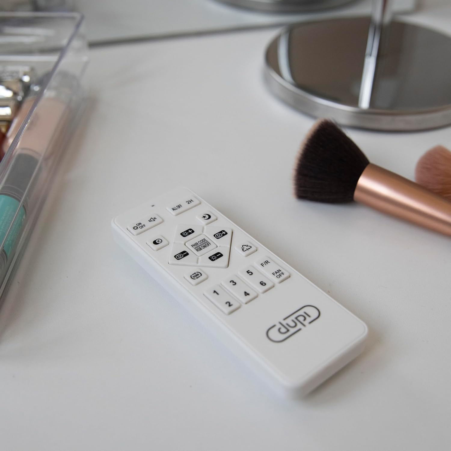 Mando a distancia blanco sobre una superficie blanca con brochas de maquillaje y otros objetos.