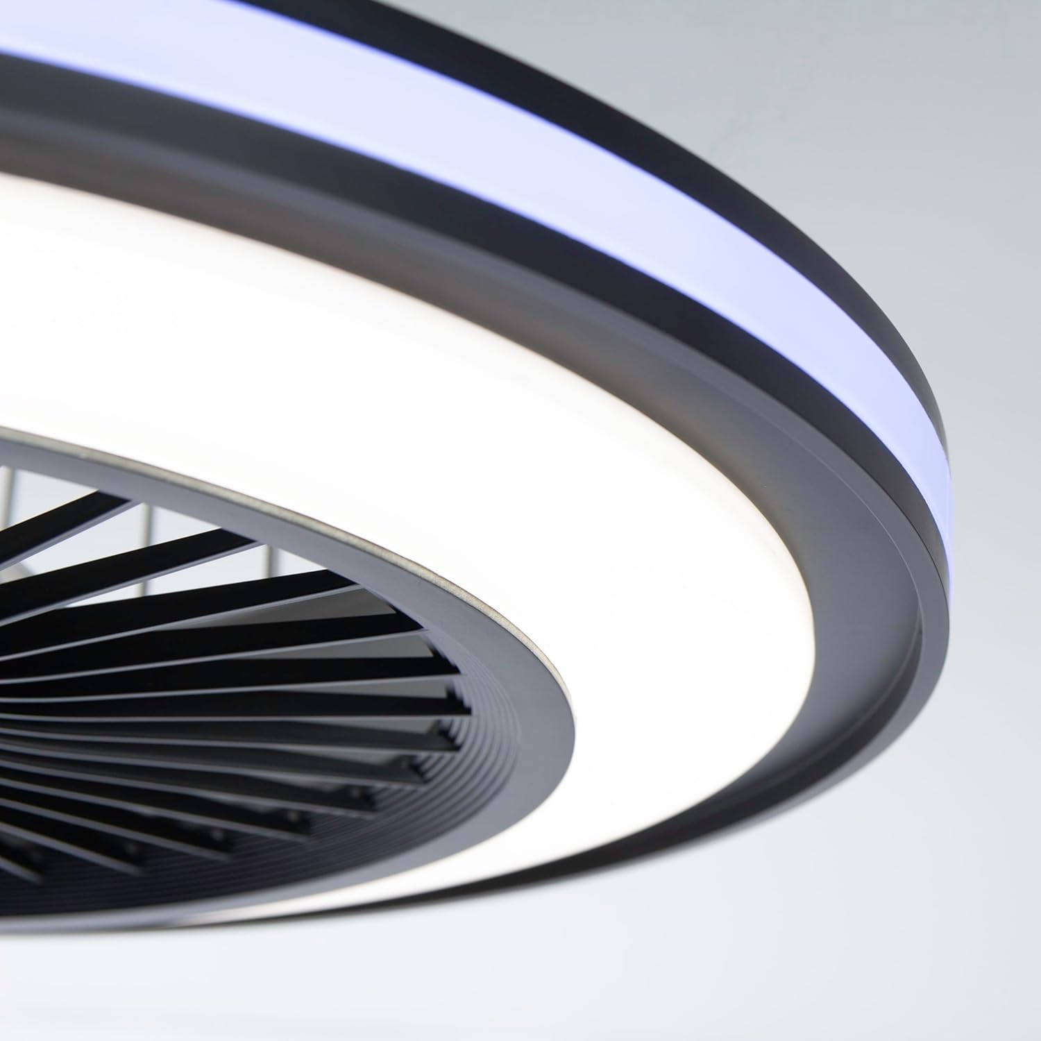 Primer plano de un ventilador de techo con luz circular y aspas negras.