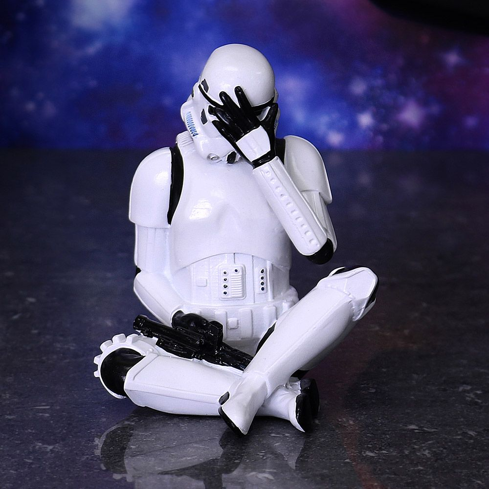 Een witte Stormtrooper figuur in een zittende pose, bedekt gezicht met hand. Donkere achtergrond.