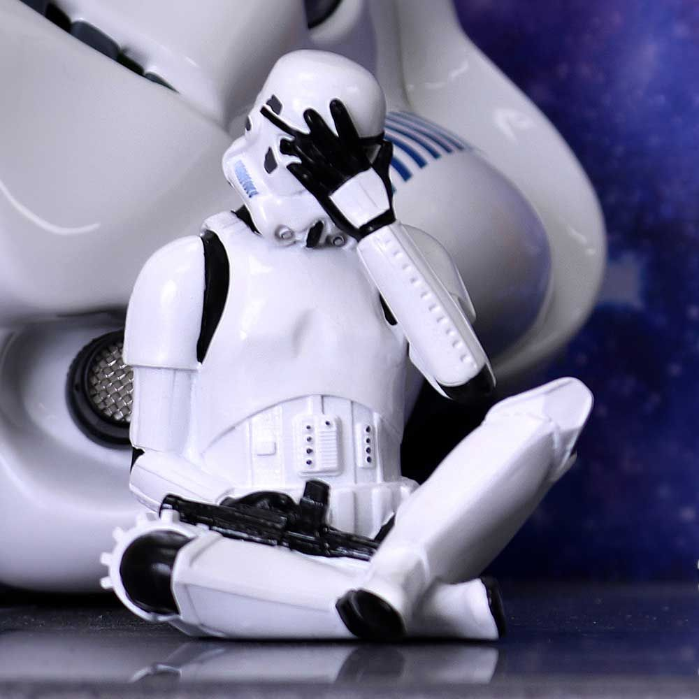 Een Stormtrooper-beeldje. Het is wit met zwarte details, hoofd in de handen, zittend op de grond.