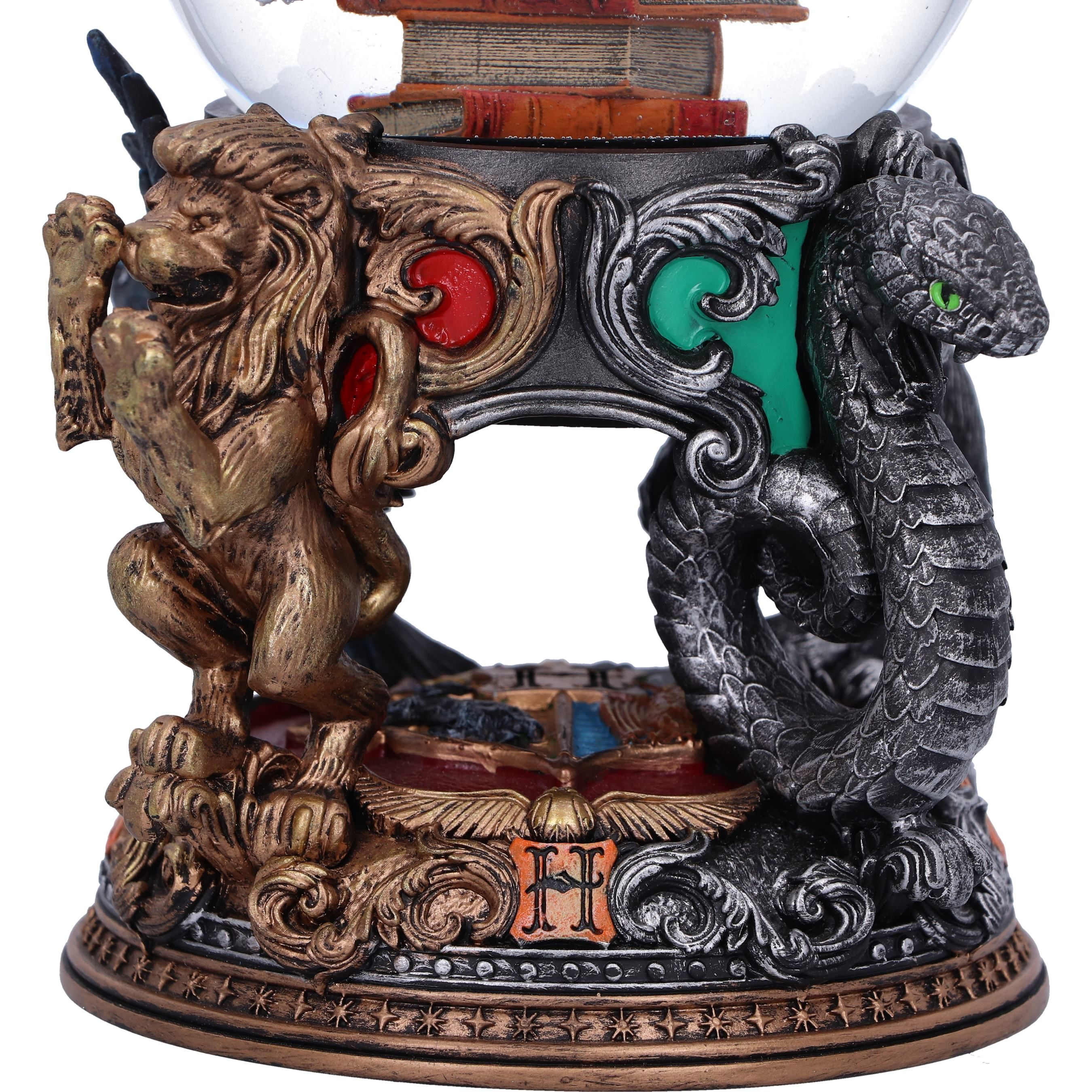 Snow globe with lion, snake, and books inside. Detailed base with ornate design. Glass globe on top.