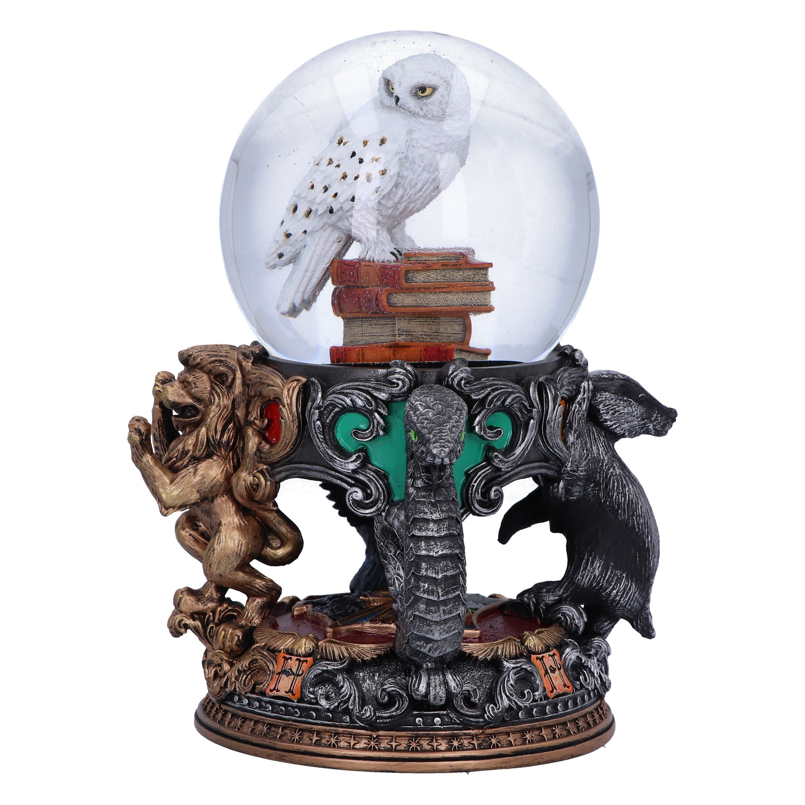 A Harry Potter snow globe with an owl on books, lions, snakes, and a badger base, on a white background.