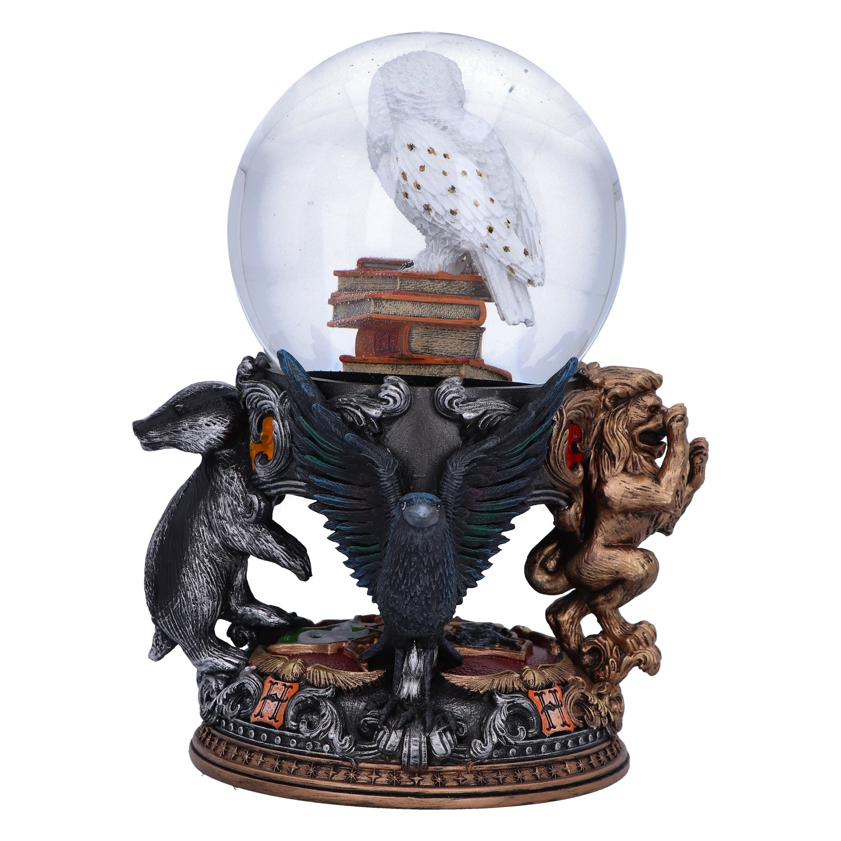 A snow globe with a white owl on books, surrounded by statues of animals.