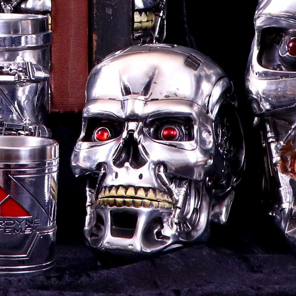 A Terminator skull with red eyes and exposed teeth. It is chrome and metallic, in a dark setting.