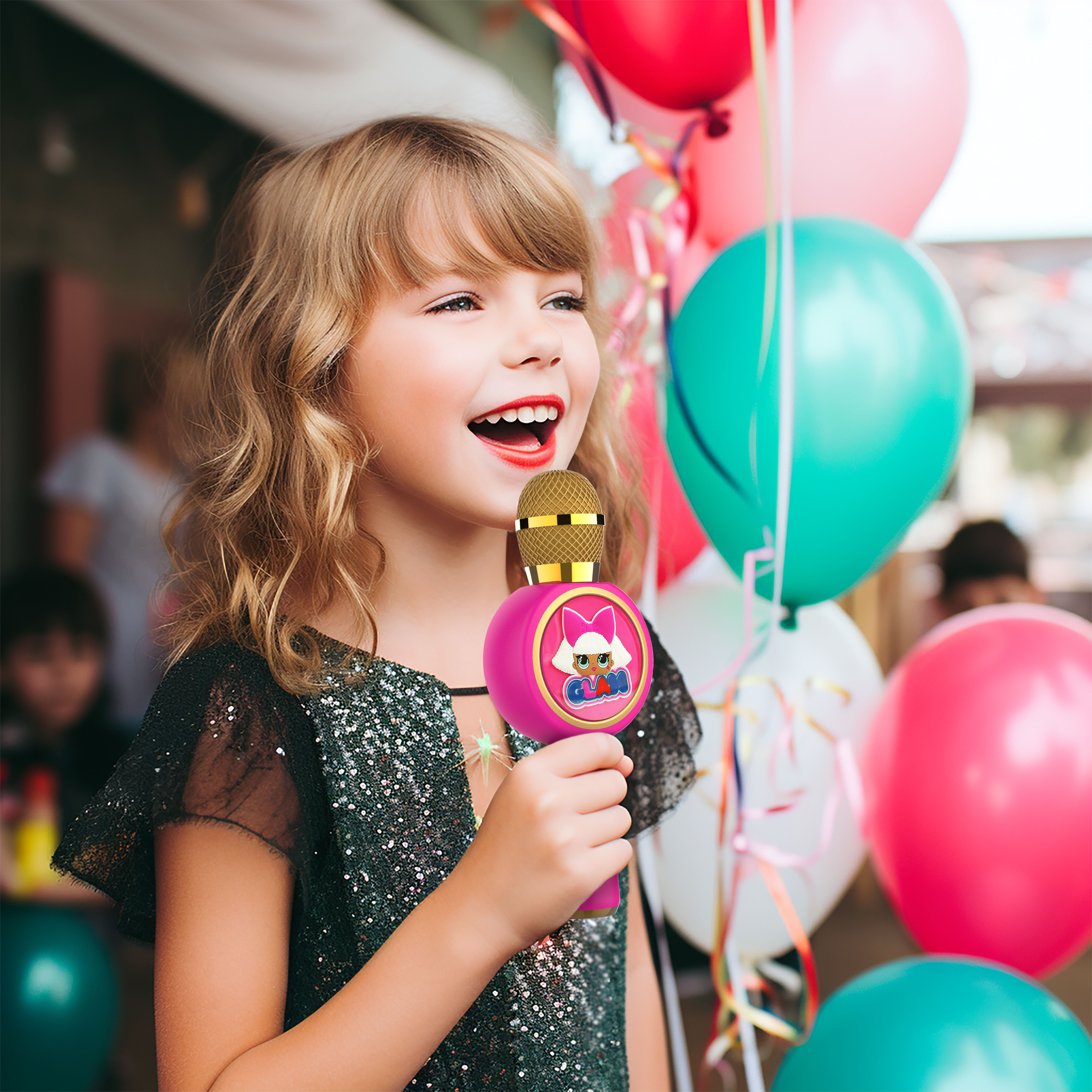 A young girl singing into a pink microphone. There are balloons in the background.