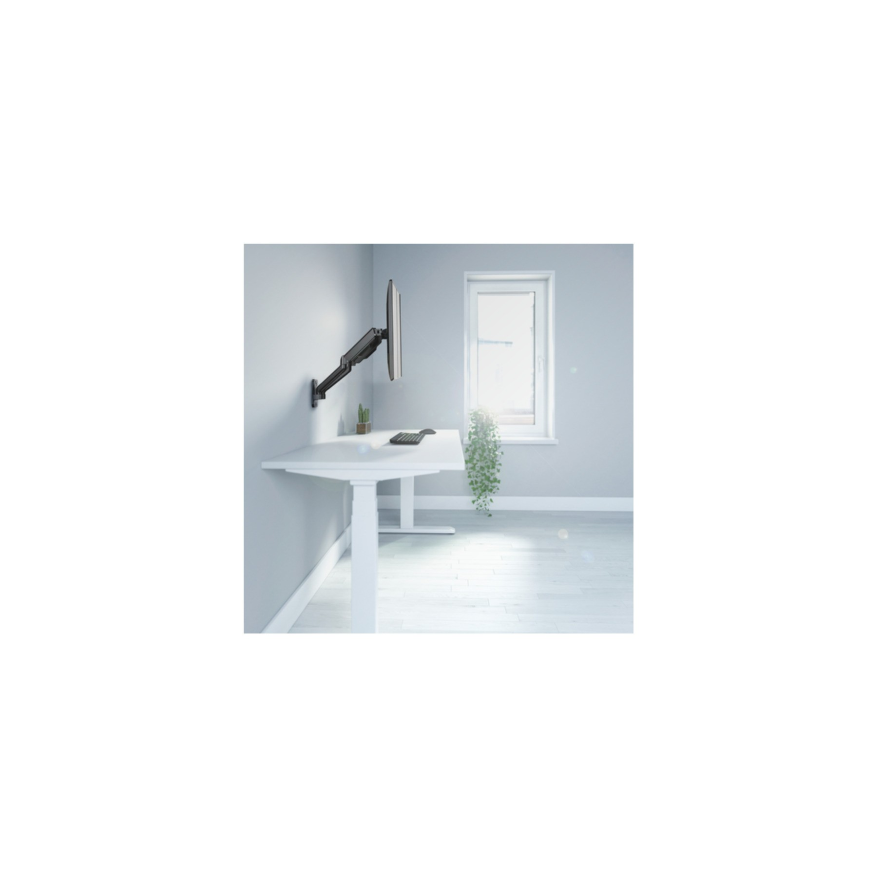 A monitor on a white desk in a room with a window. The monitor is mounted on the wall.