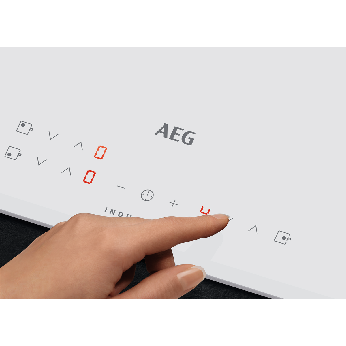 Mano che tocca un piano cottura a induzione bianco. Il display rosso mostra il livello di potenza.