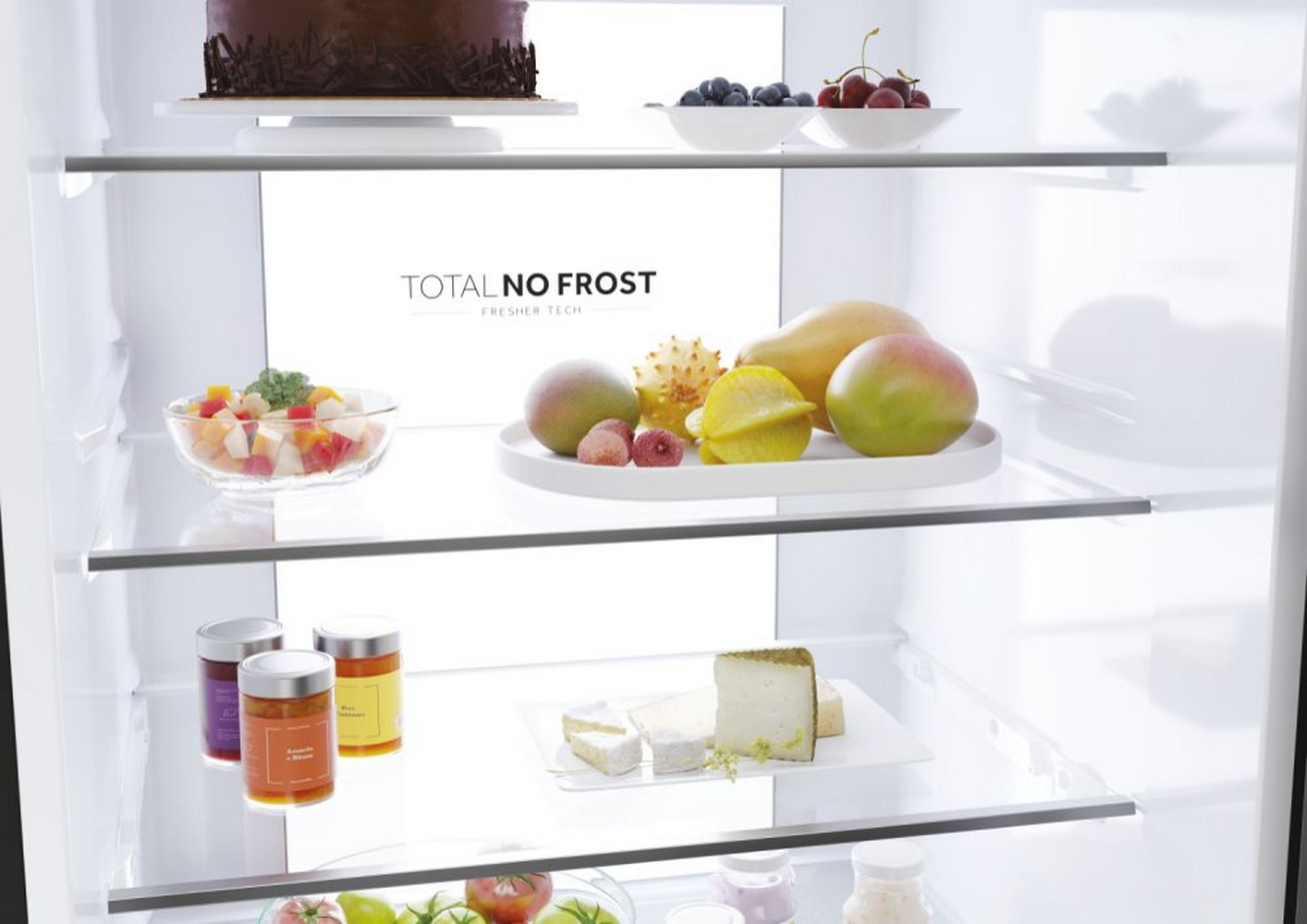 Kühlschrankinnenraum mit Regalen. Enthält einen Kuchen, Früchte und Gläser mit Lebensmitteln. Der Text "TOTAL NO FROST" ist sichtbar.