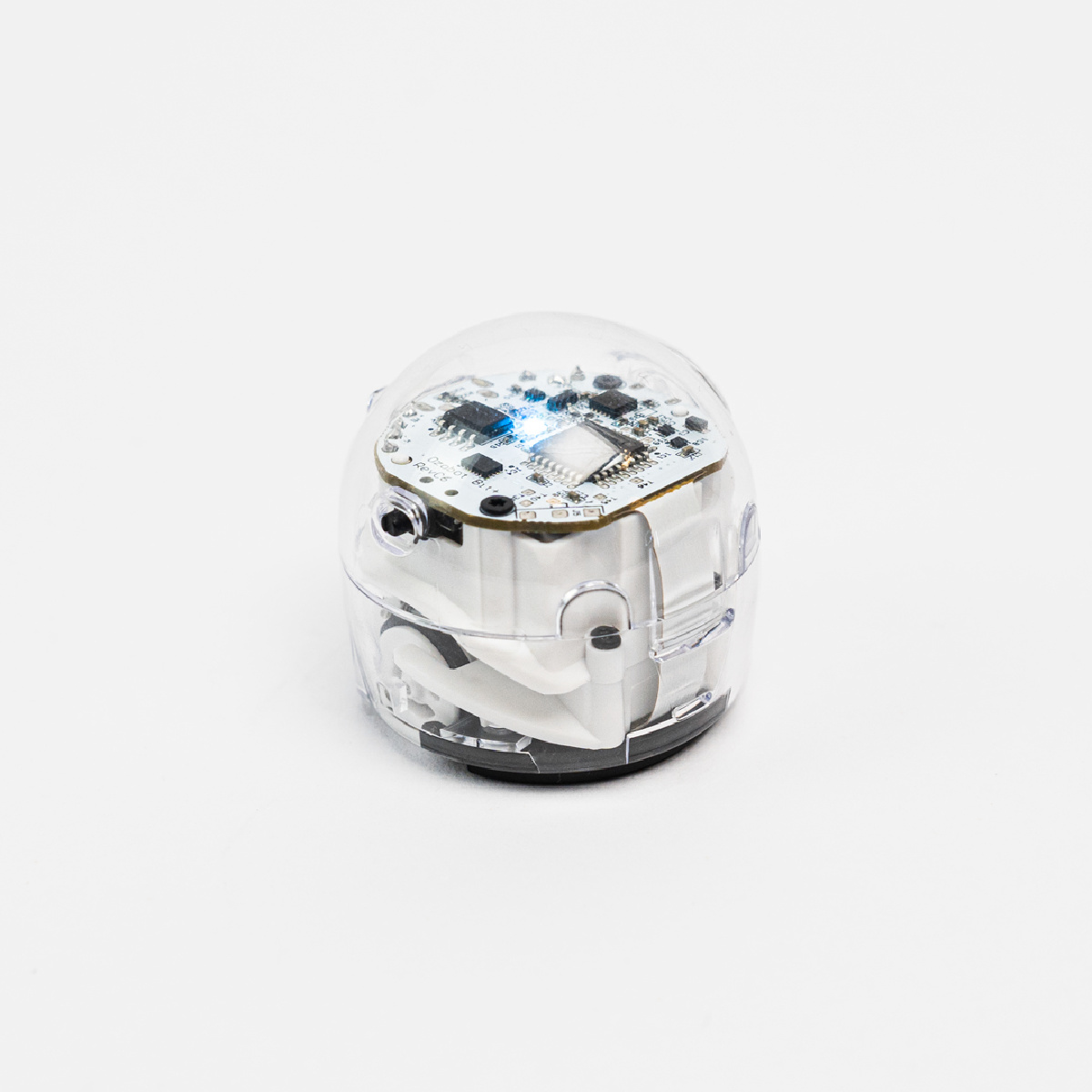 A clear, spherical robot with its internal components visible. It is on a white surface.