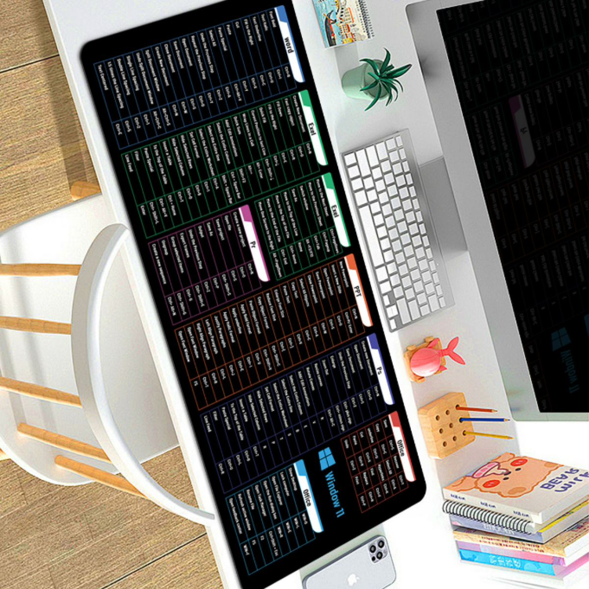 Configurazione della scrivania con tastiera, tappetino per il mouse e monitor. Pila di libri e telefono.