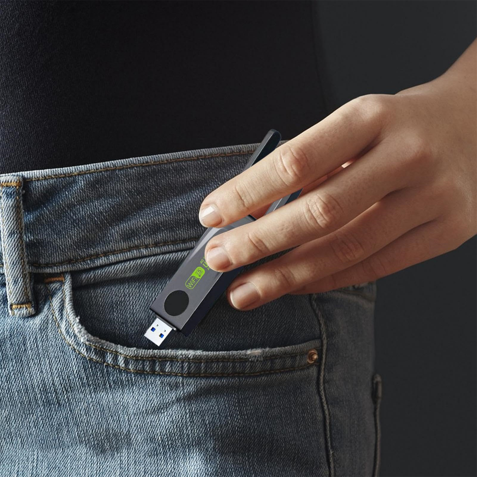 Die Hand einer Person, die einen schwarzen USB-Stick in einer Jeans-Tasche hält.