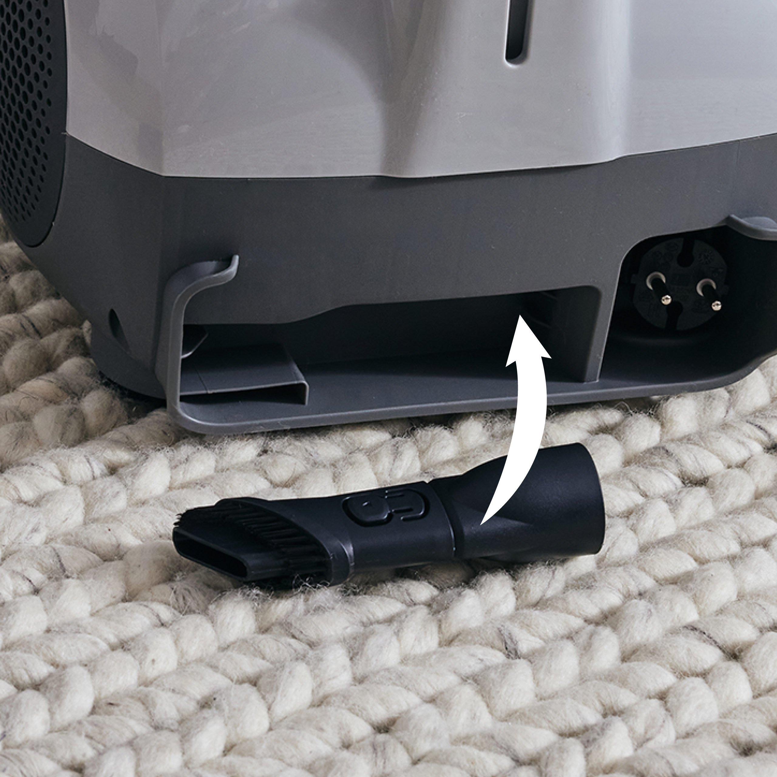 Odkurzacz z nakładką szczotkową. Strzałka wskazująca na szczotkę do mocowania. Biały tkany dywan.